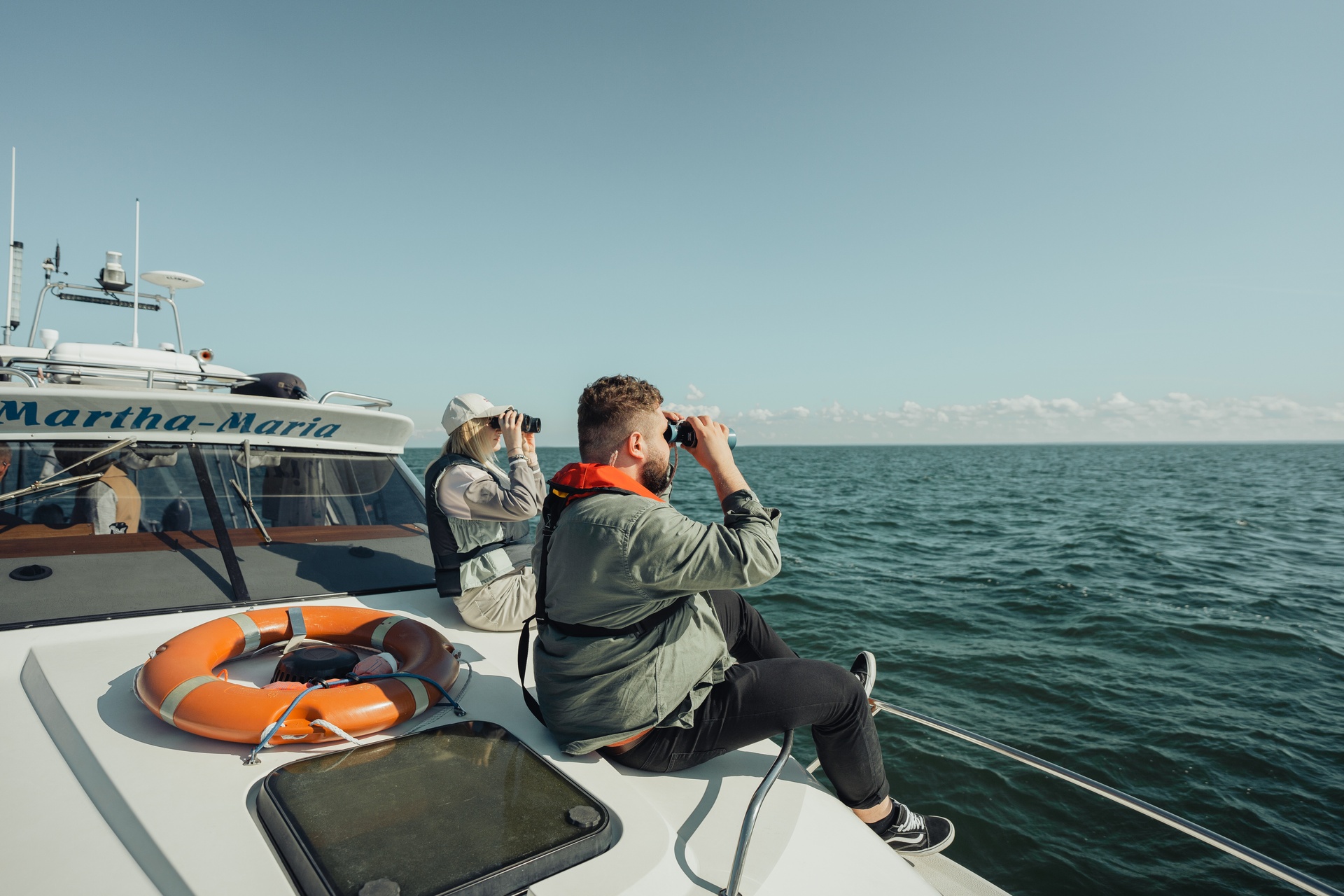 Visitors use binoculars to see seals from a boat in Estonia.
