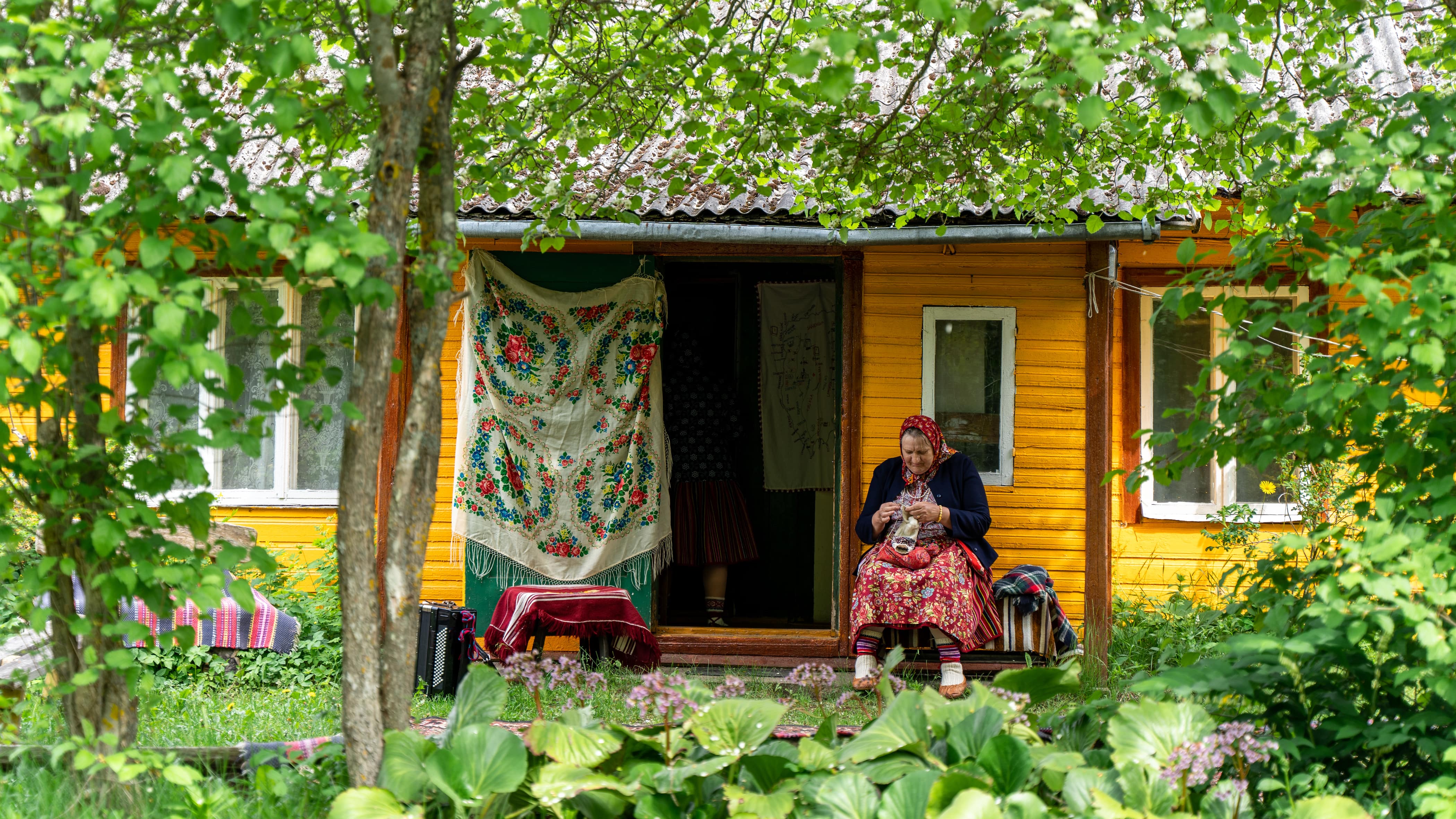Woman knitting in front of traditional house on Kihnu Island