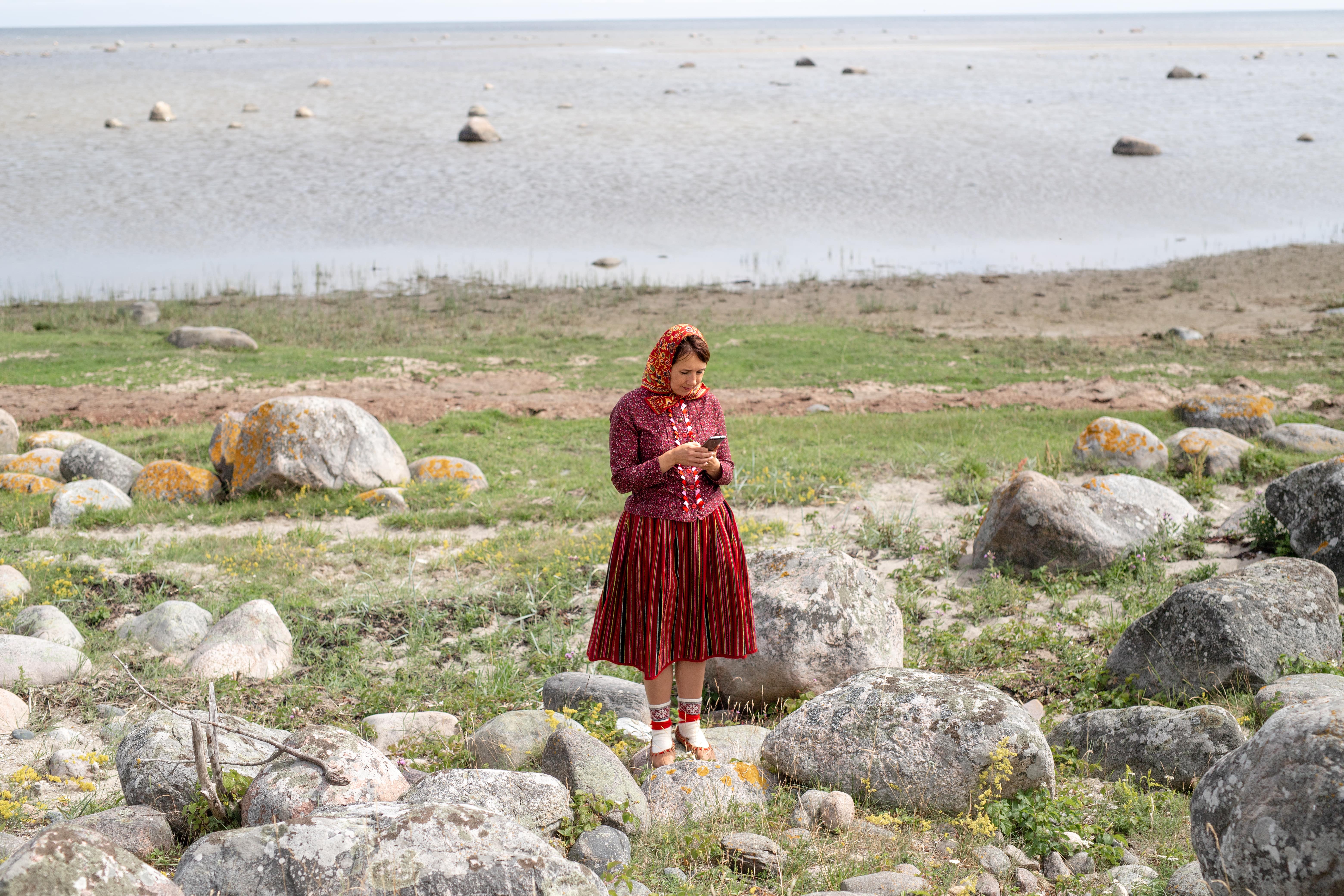 Kihnu woman in traditional dress checking phone