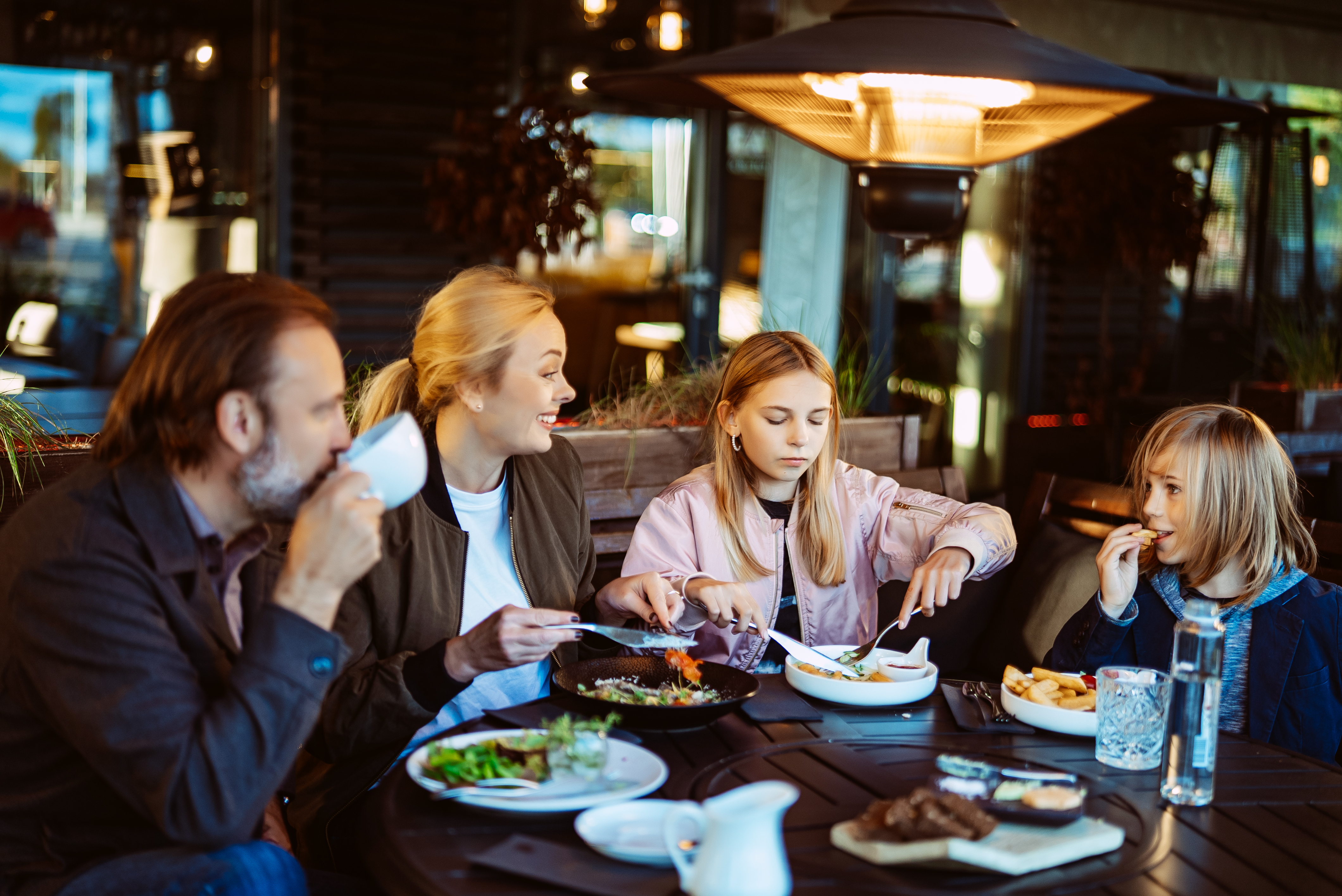 Mom, dad, son and daughter eat at a restaurant in Estonia