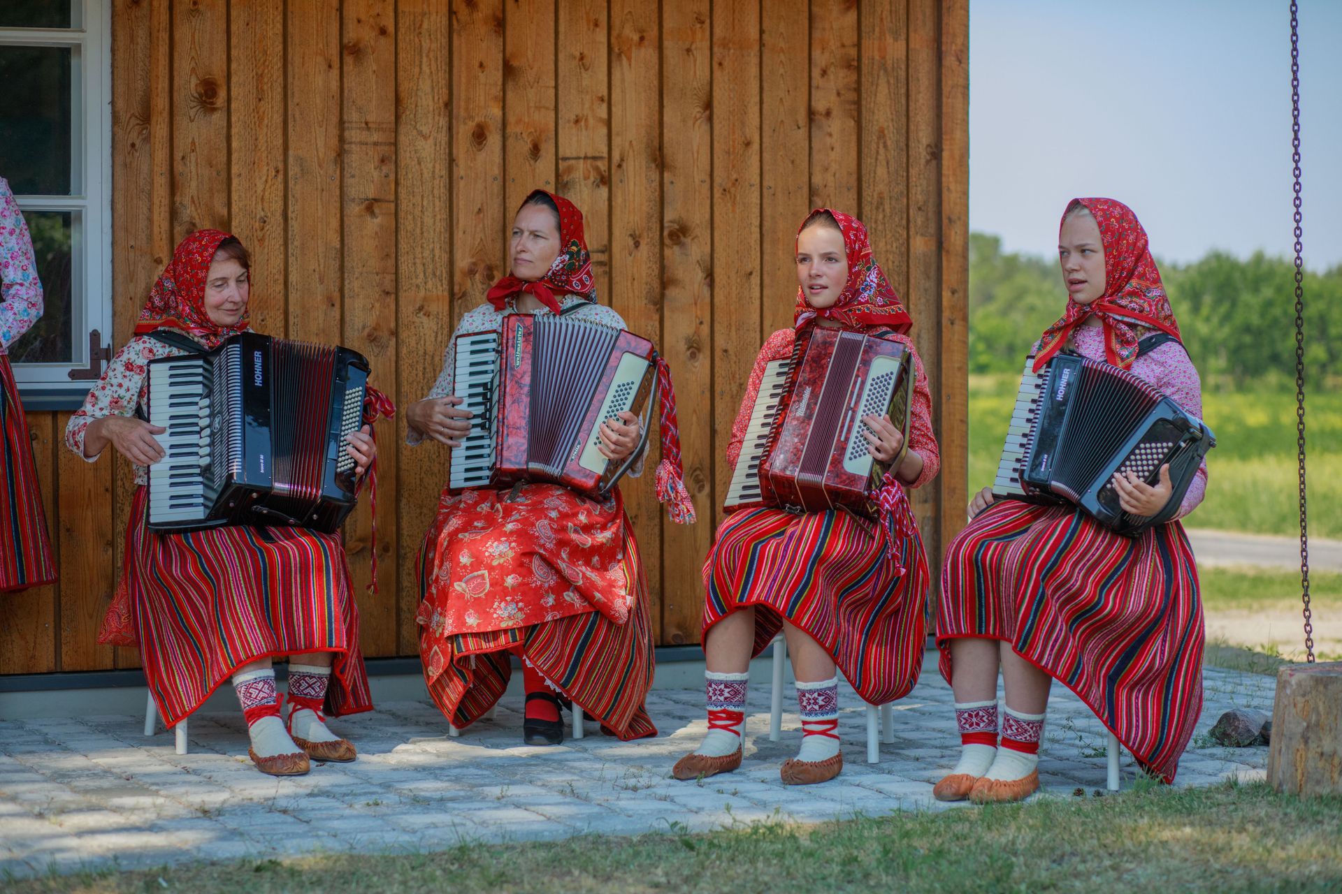 Kihnu naised kohalikes rahvariietes mängivad akordionit.