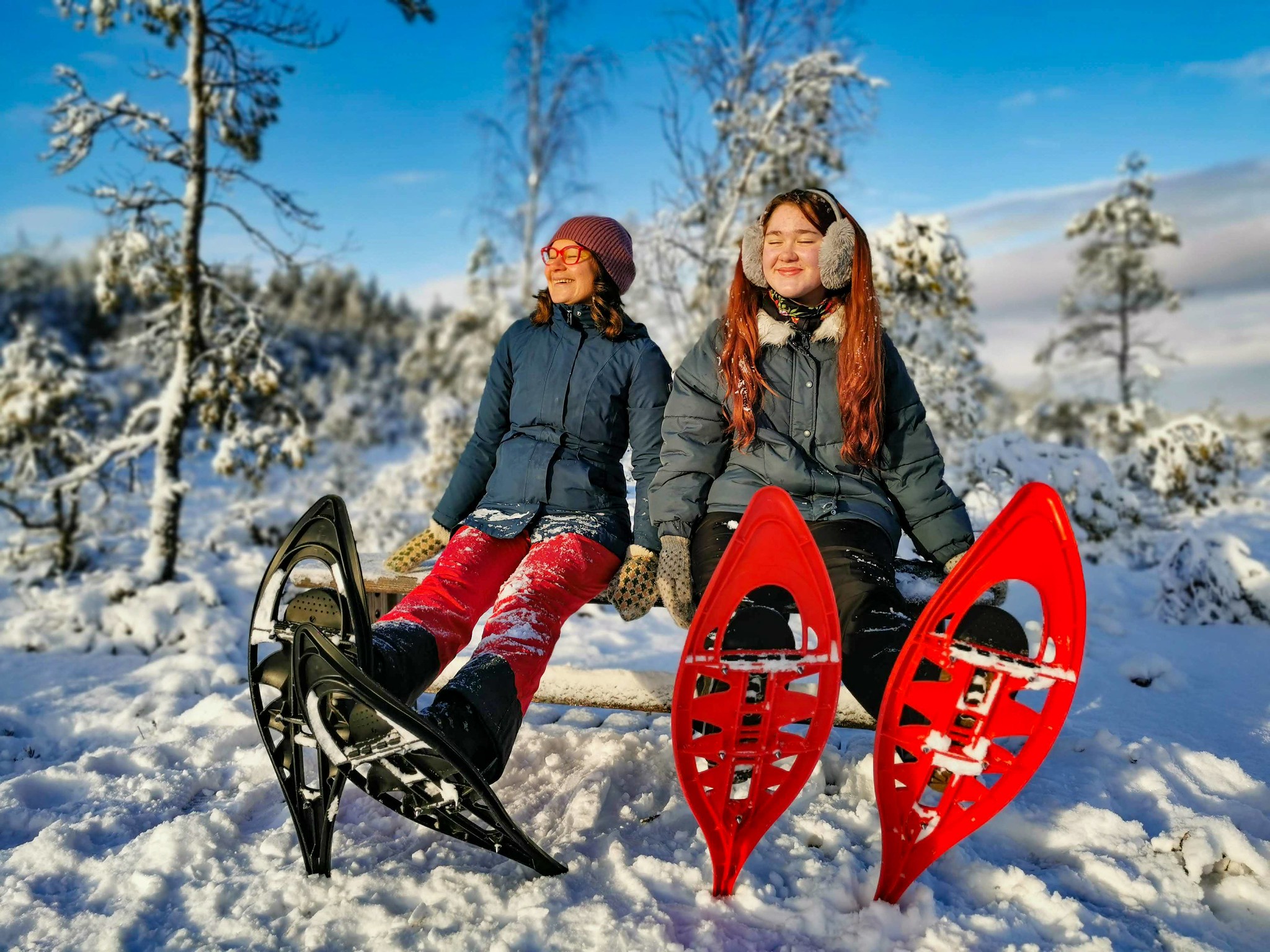 two women enjoy sunny winter snowshoe hike