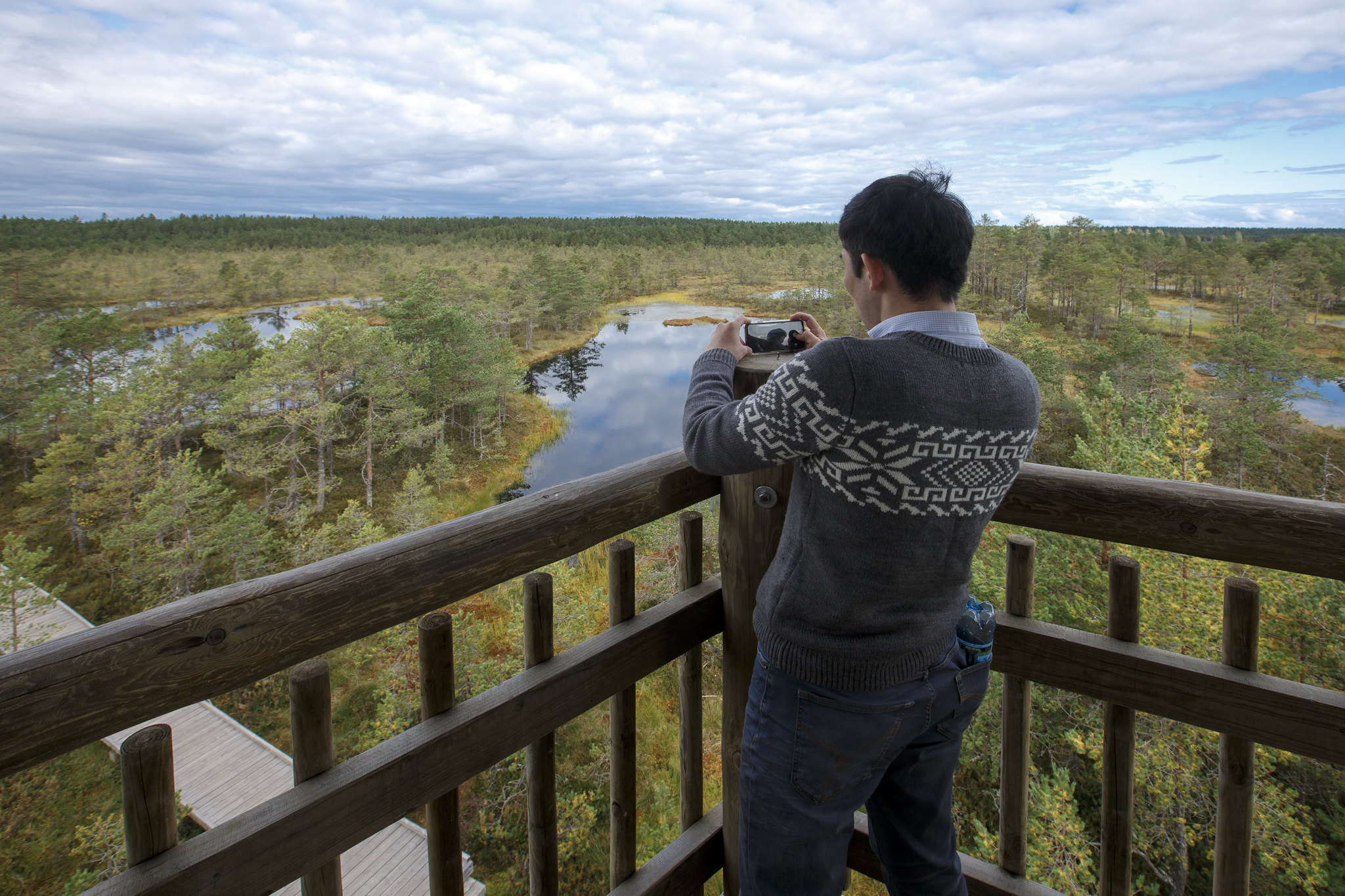 Man in gray sweater takes photos of Viru Bog from tower