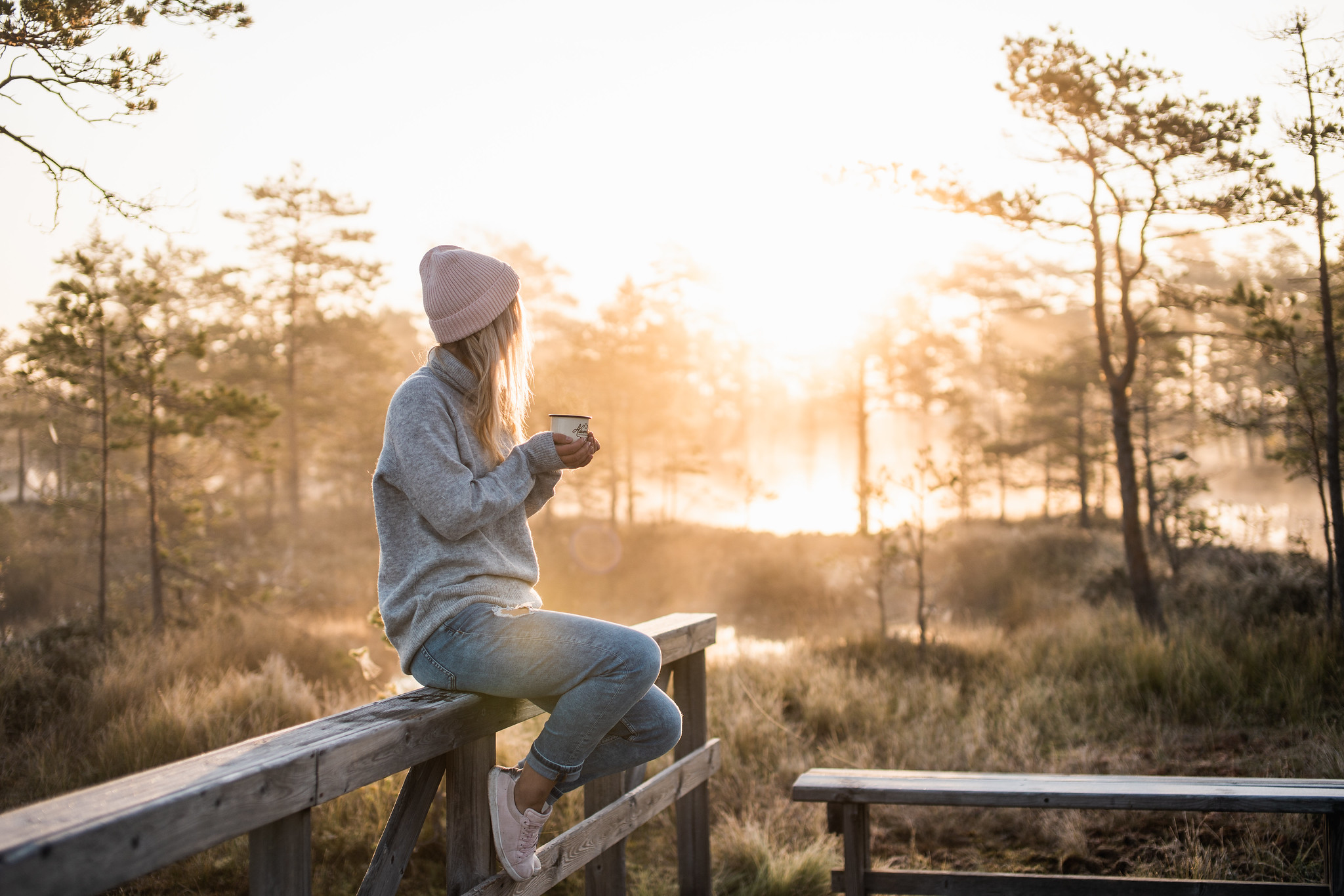 Woman enjoys coffee at sunrise in a bog in West Estonia