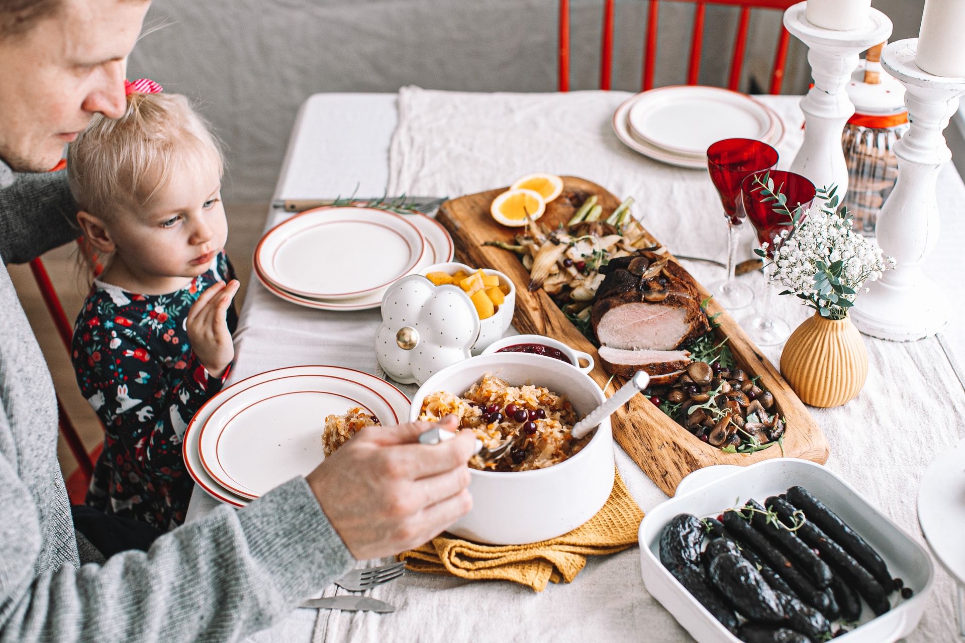 Little girl sits on father's lap for Christmas dinner