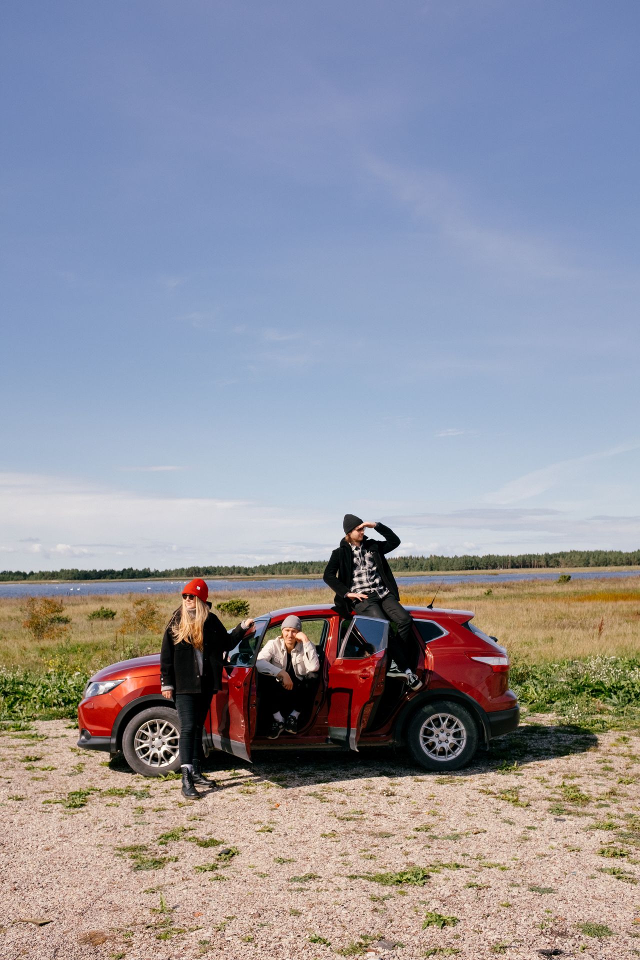 group of friends and red car near a lake in Estonia