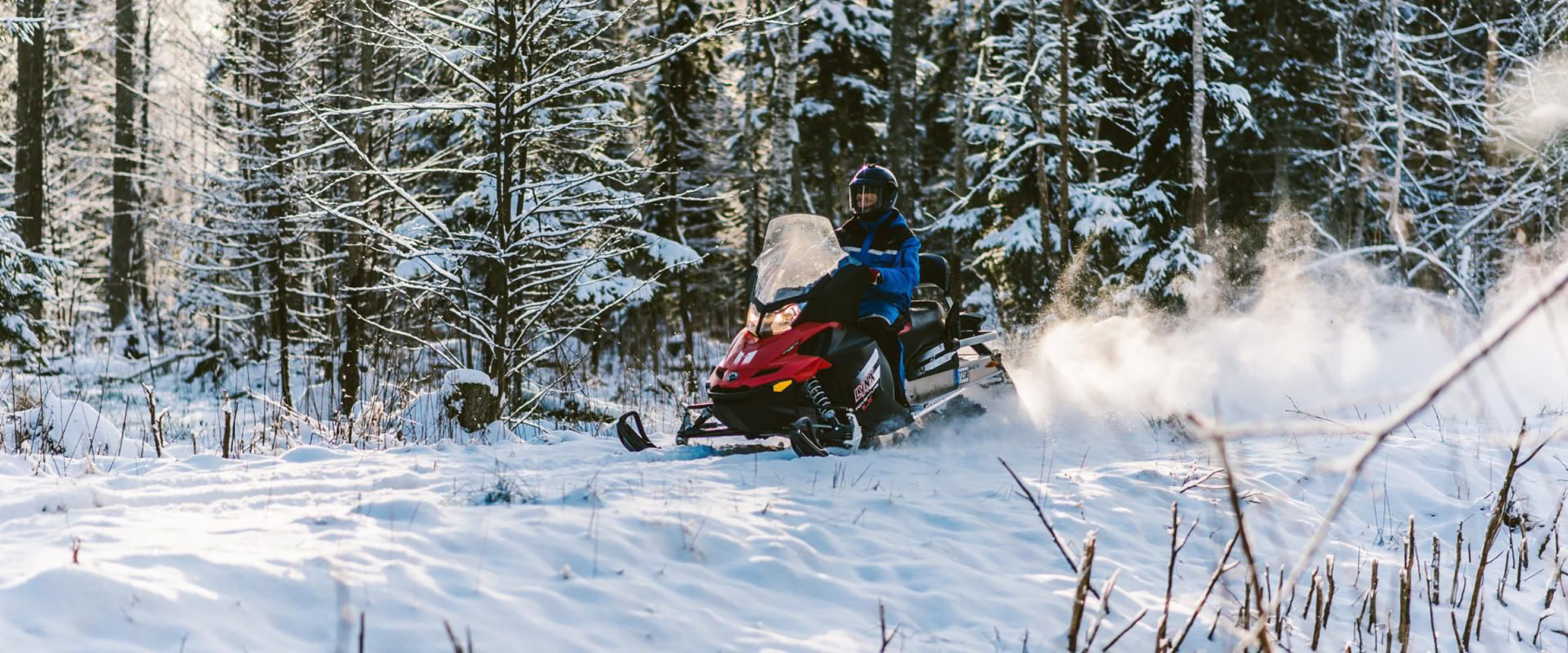 Moottorikelkkasafarille osallistuja metsässä 