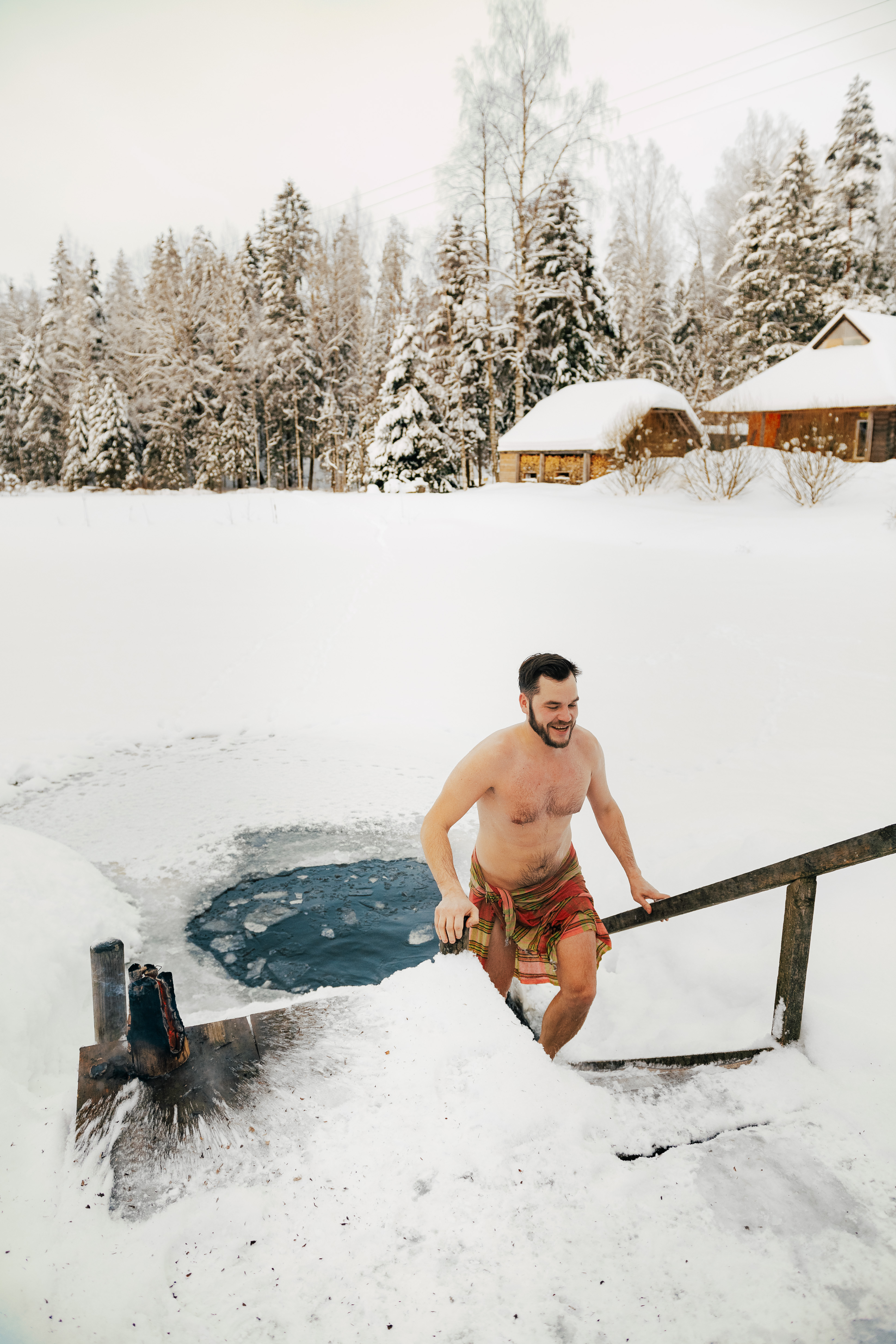 Man emerging from ice hole swim wearing towel