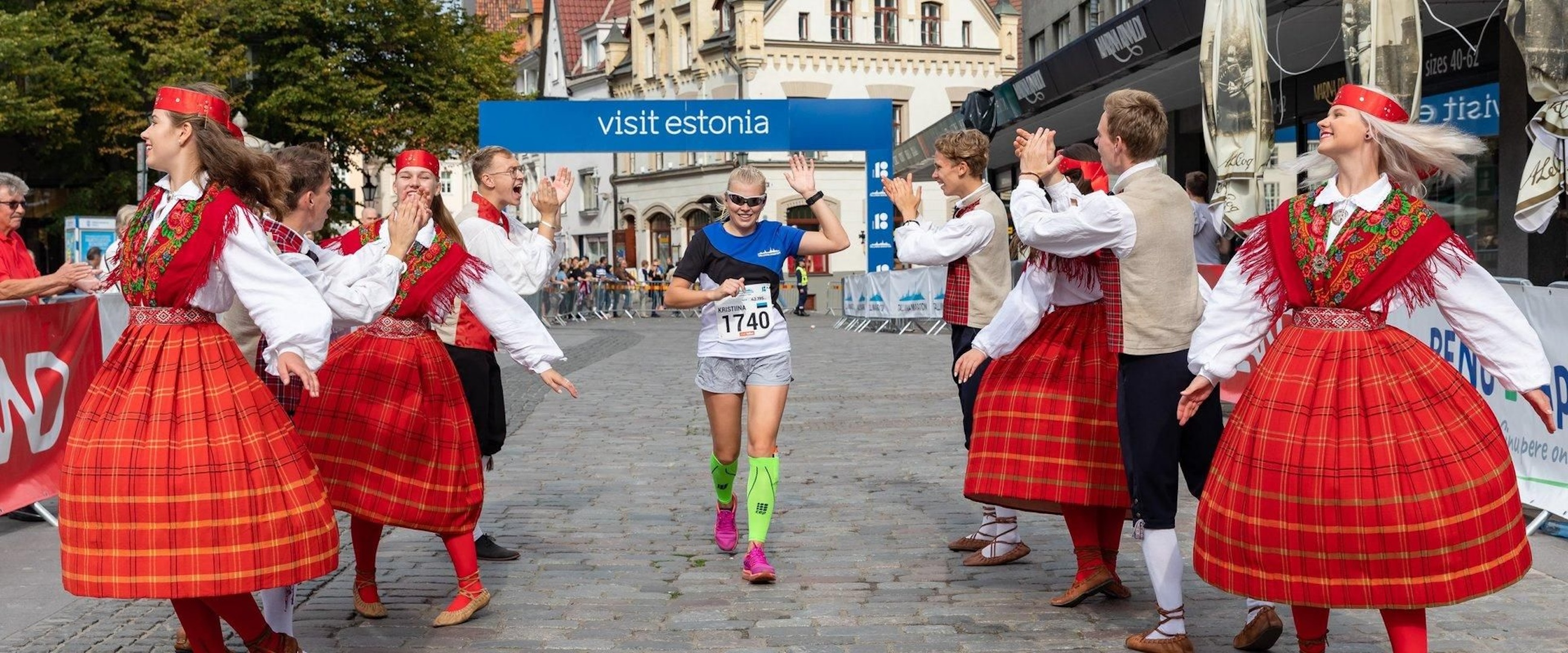 Runner jogging between traditional Estonian dancers 