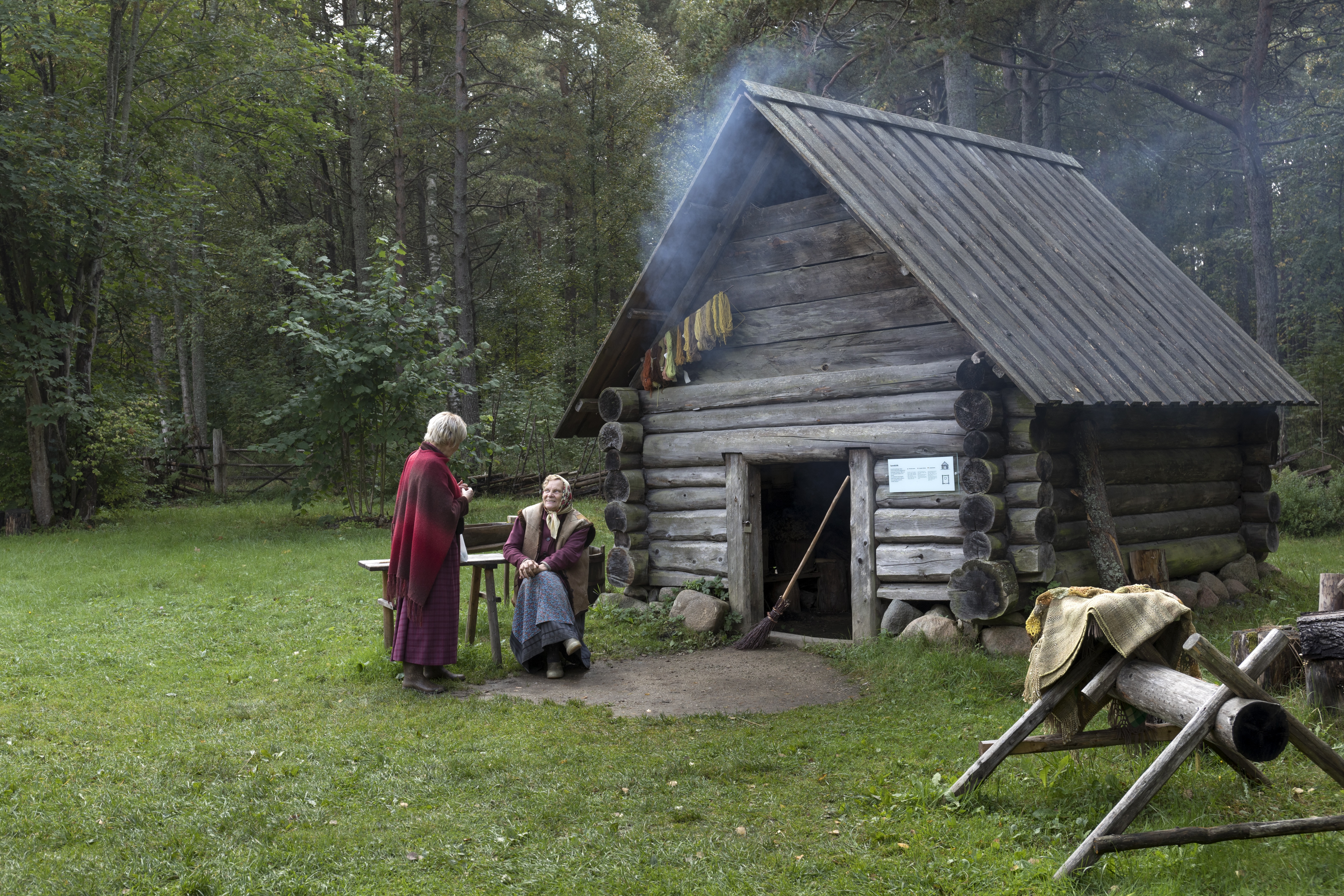 Two women speak near a cabin at Tallinn's Open Air Museum.