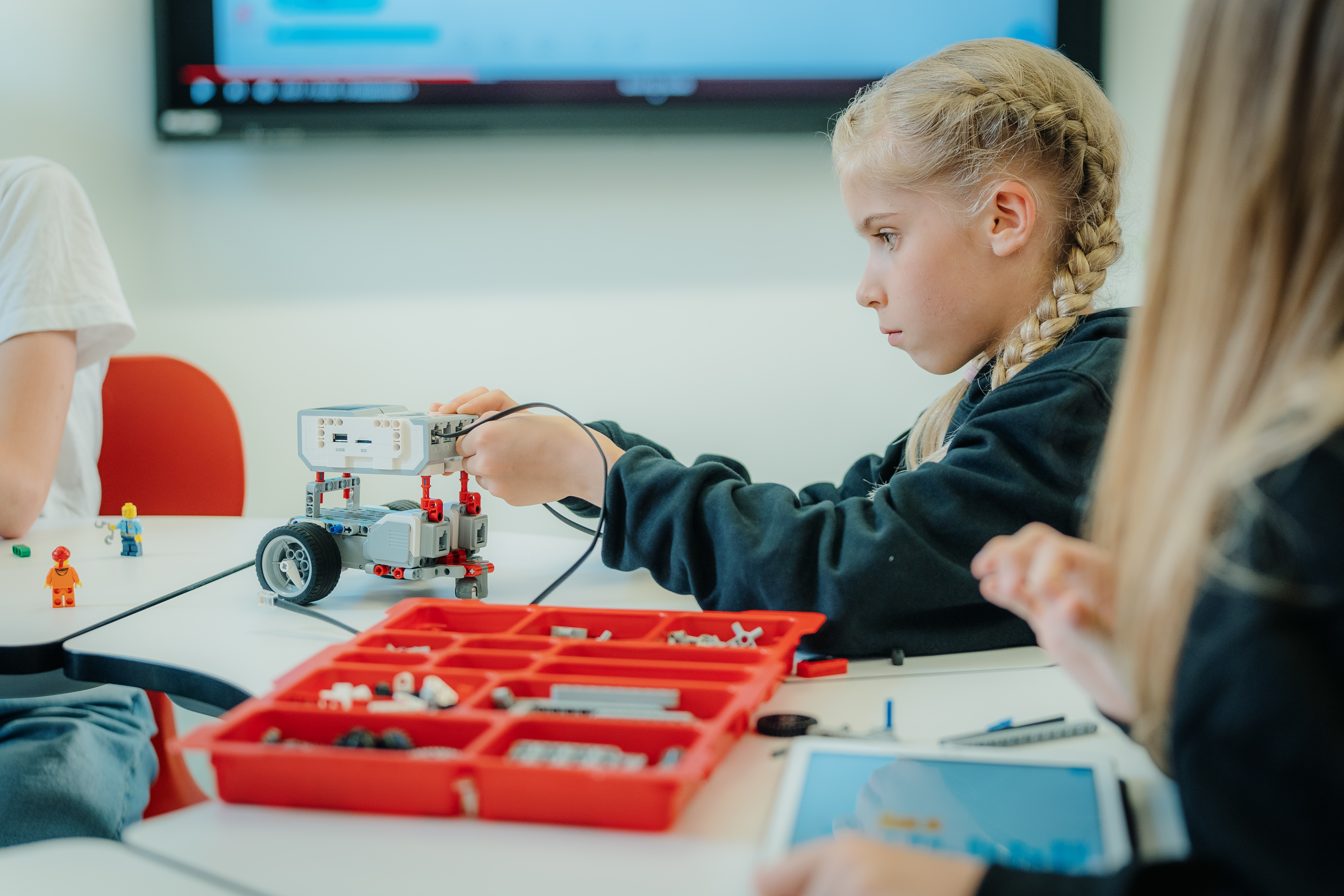 Young Estonian girl with braids building a robot