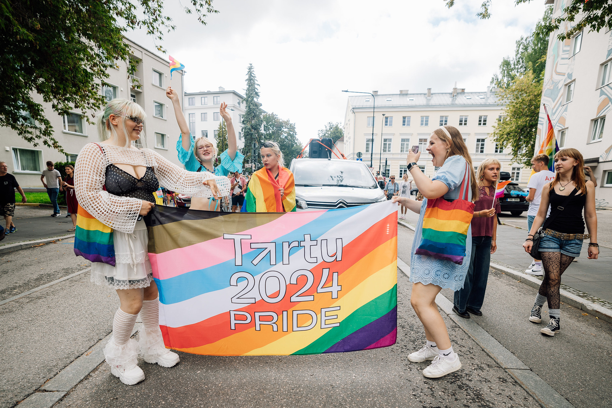 Four women and Tartu 2024 Pride flag at parade on the street