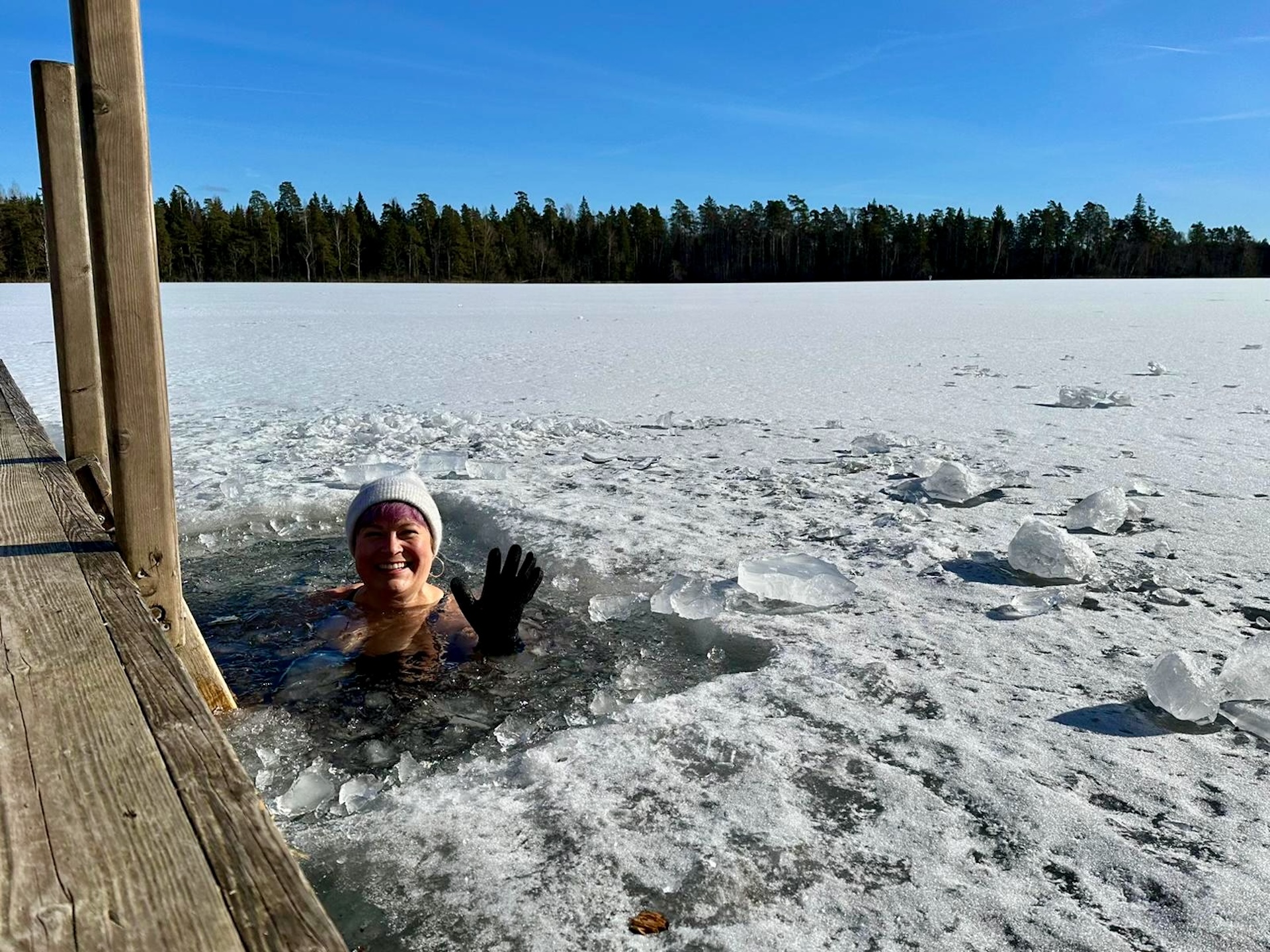 Woman swimming in frozen lake in Estonia during winter