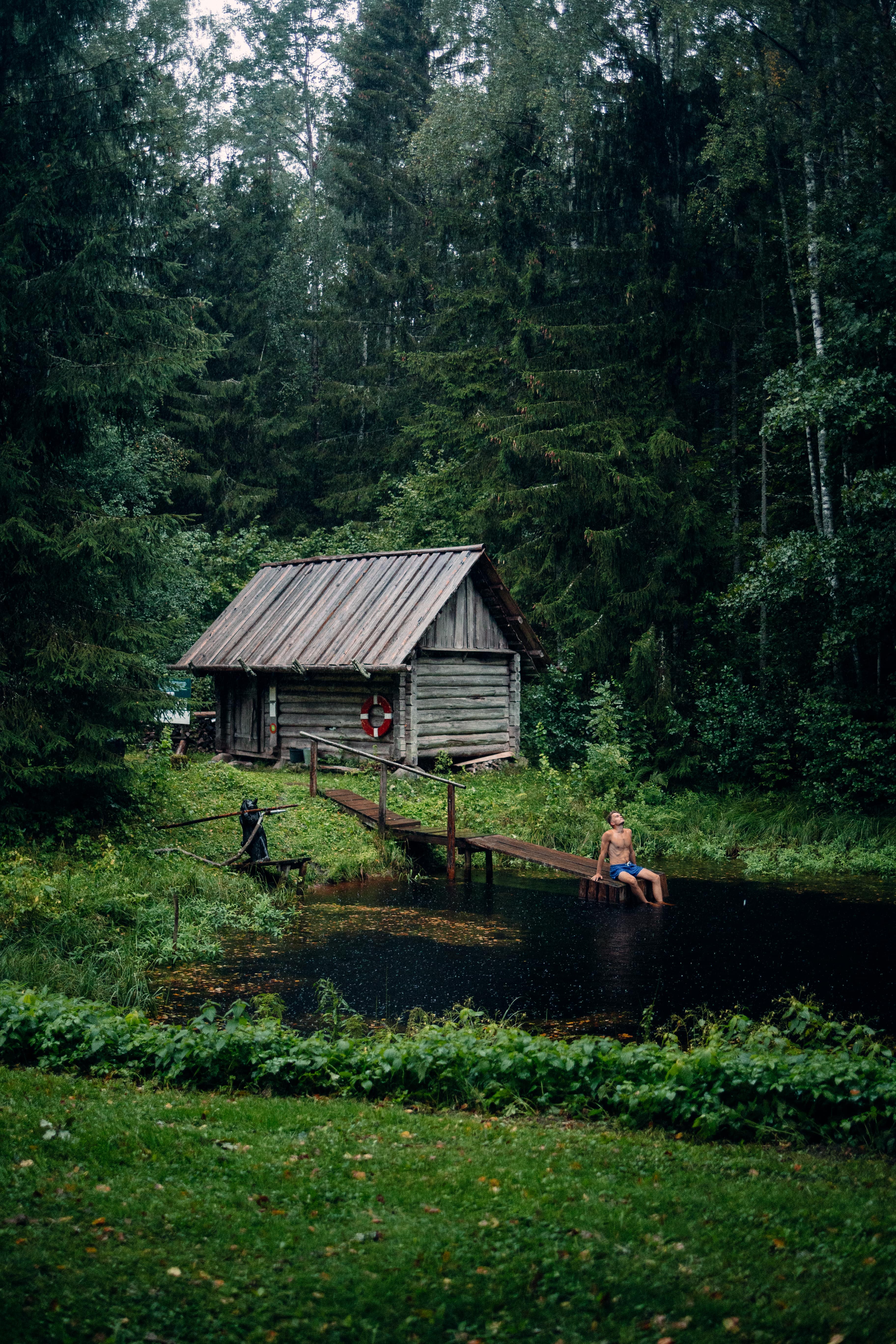 Man relaxes at pond in South Estonia by wooden building