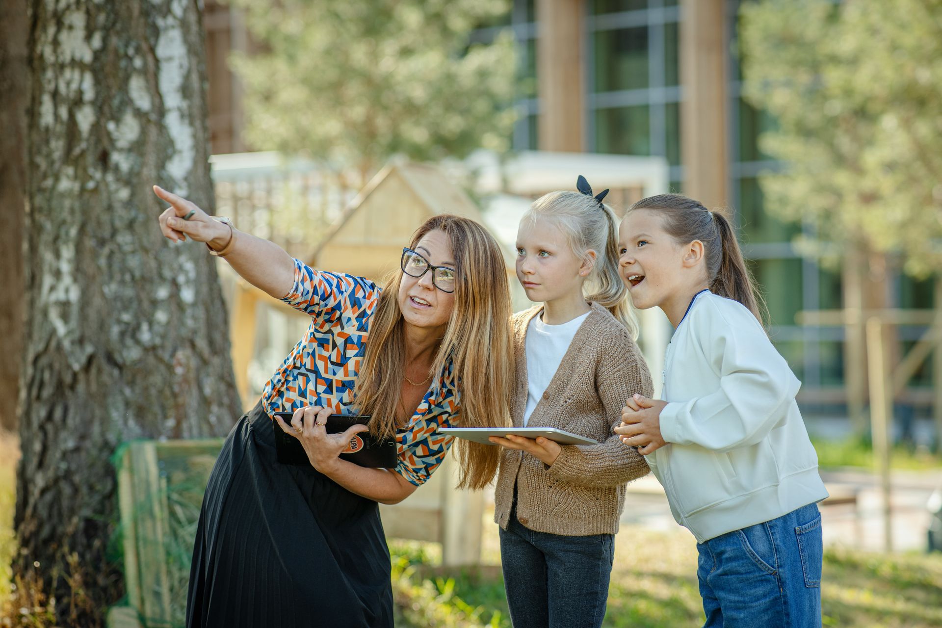 Naine näitab lastele looduses midagi osutades sellele