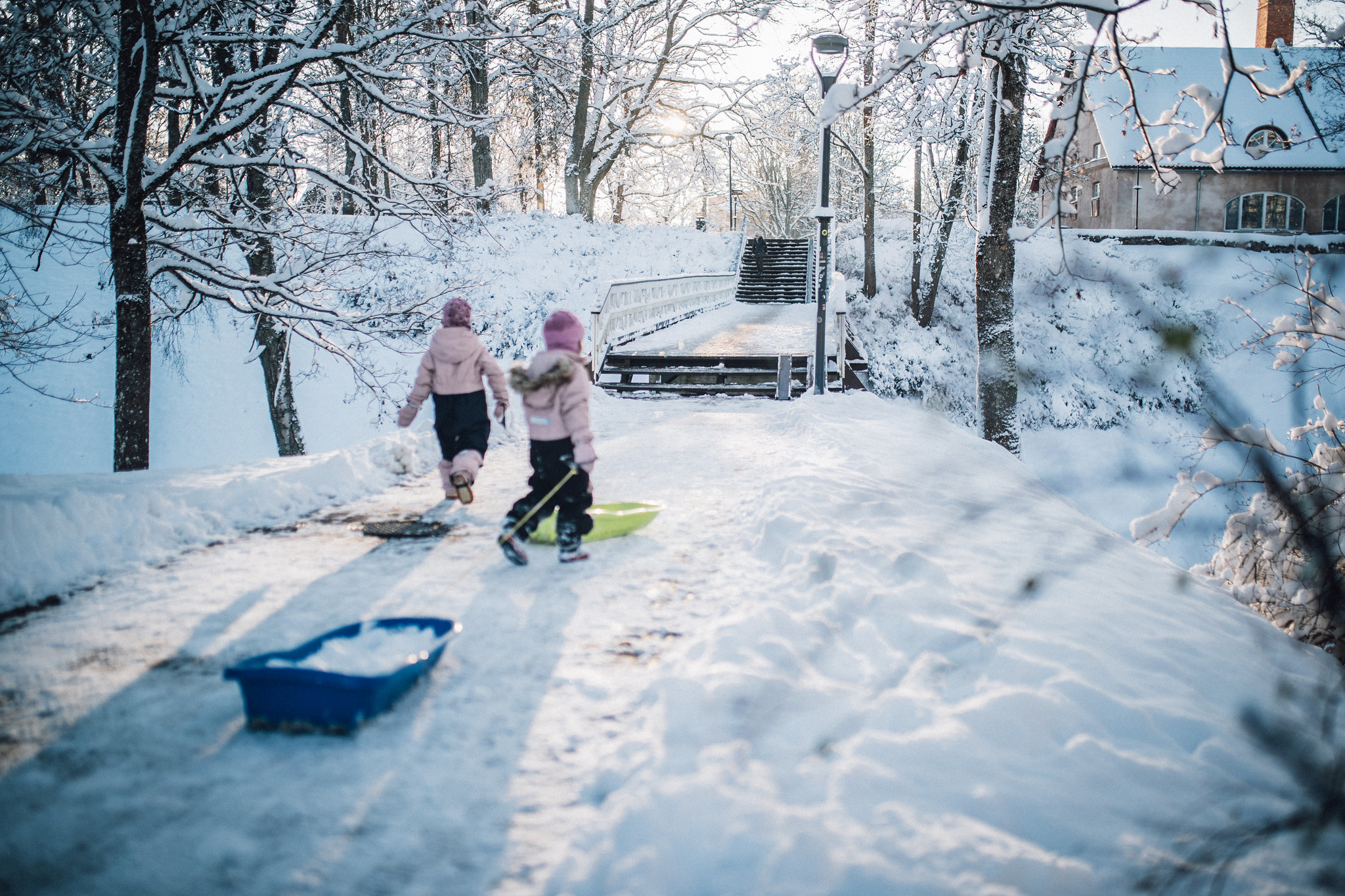 Two girls pull sleds in snowy Viljandi