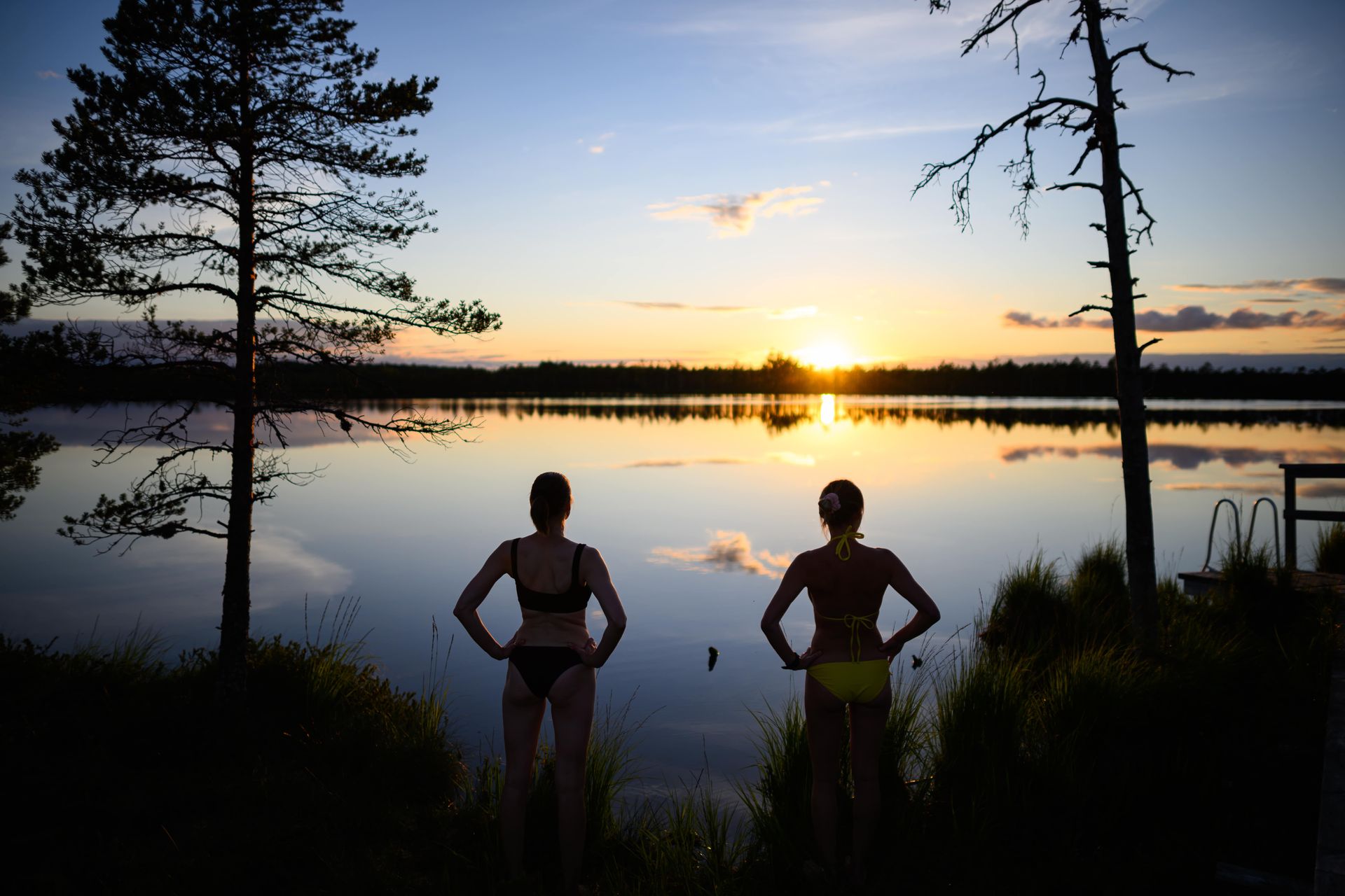 Zwei Frauen stehen bei Sonnenuntergang an einem See in Estland
