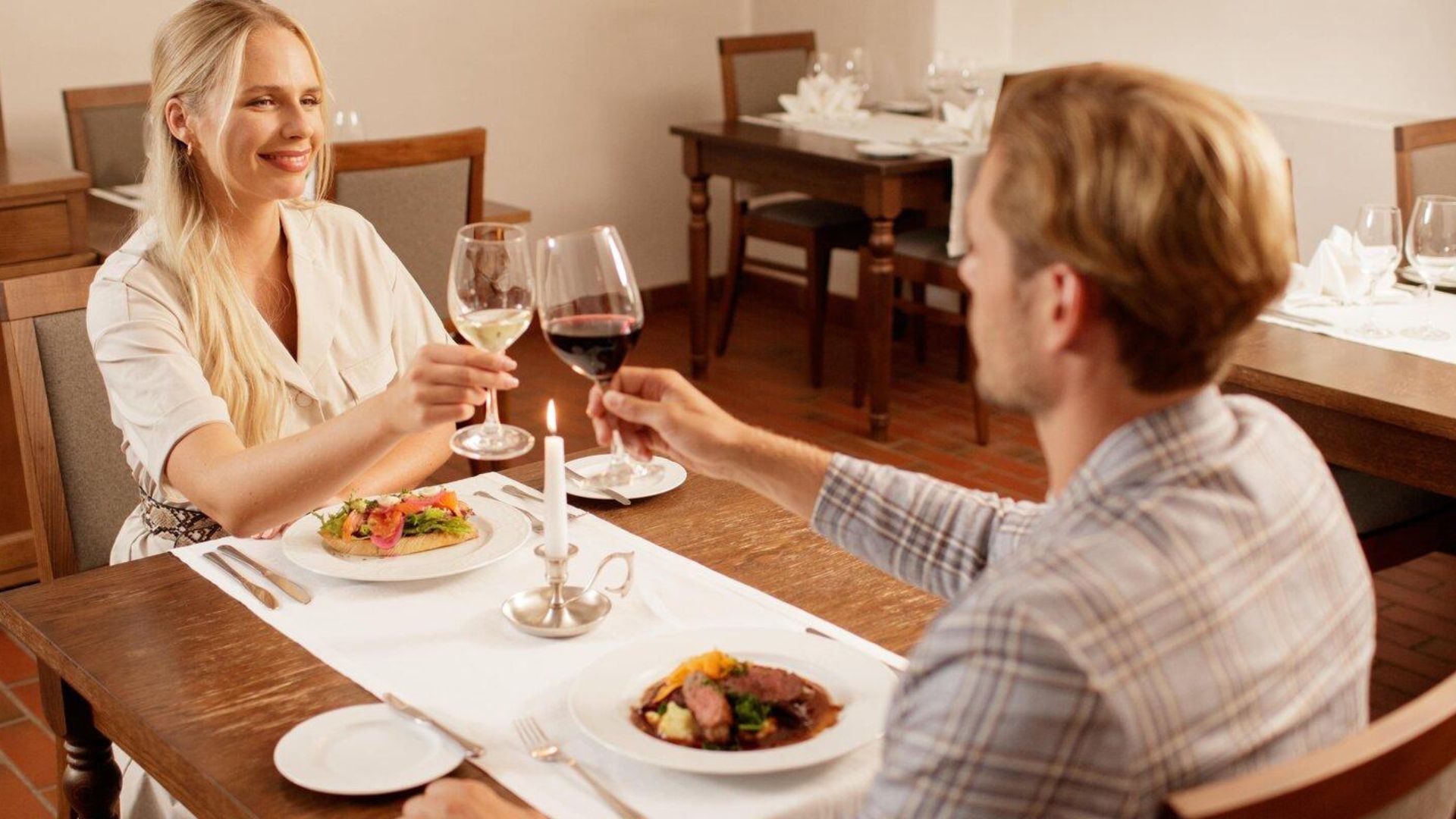 Paar tõstab klaase romantilisel õhtusöögil küünlavalgel