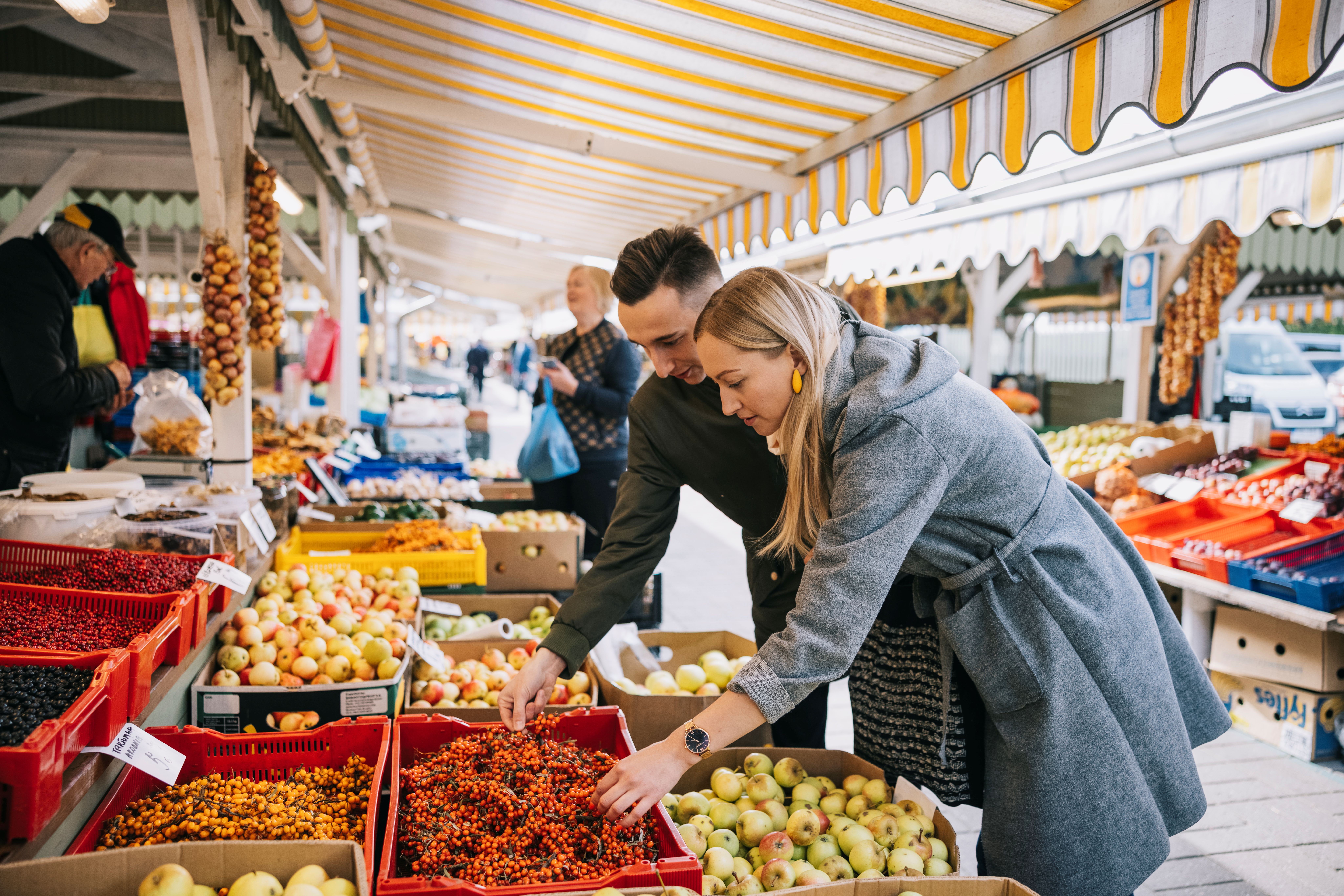 A young couple at Nõmme Market, surrounded by colorful stalls.