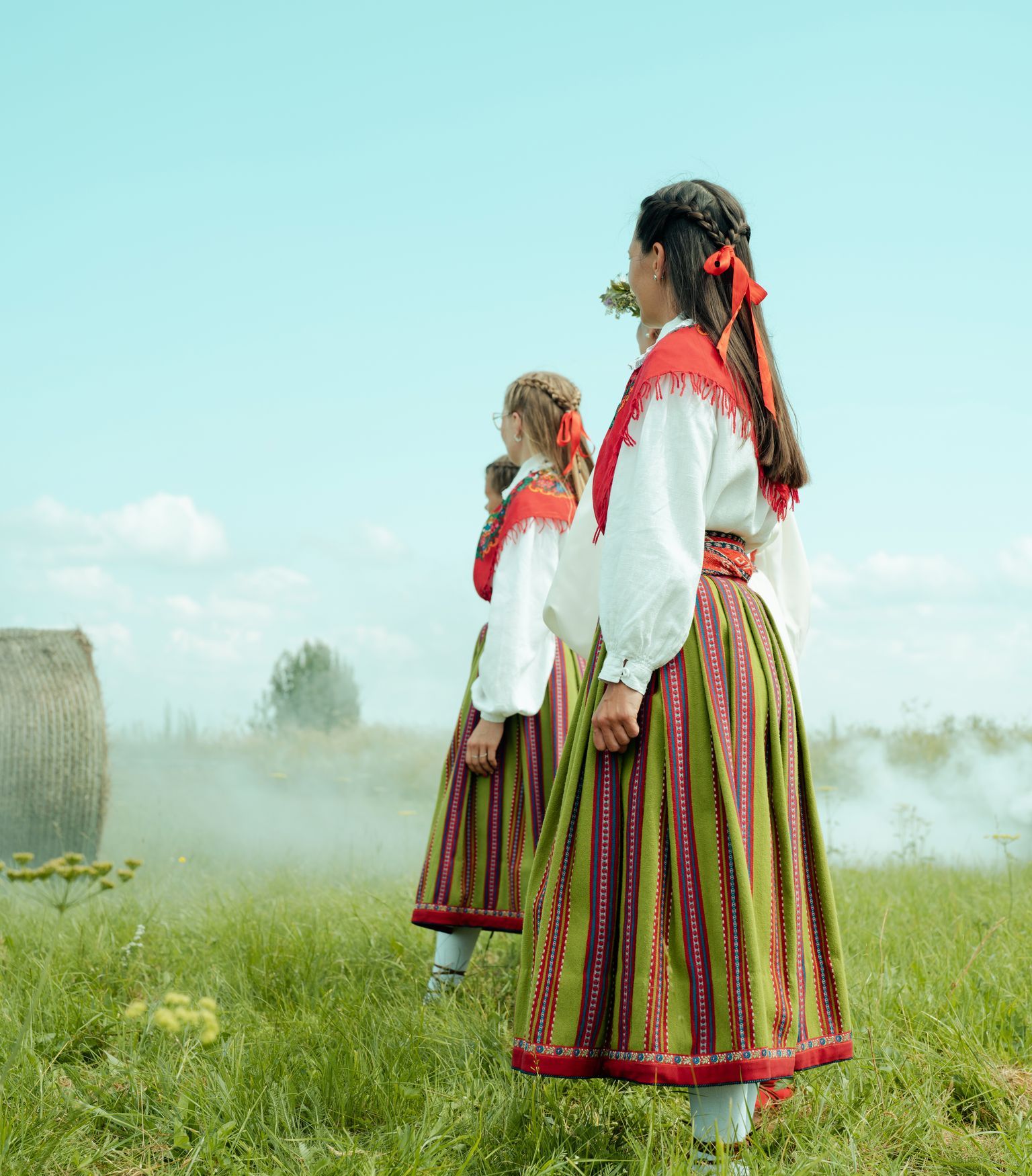 Rahvariides tüdrukud seisavad heinamaal
