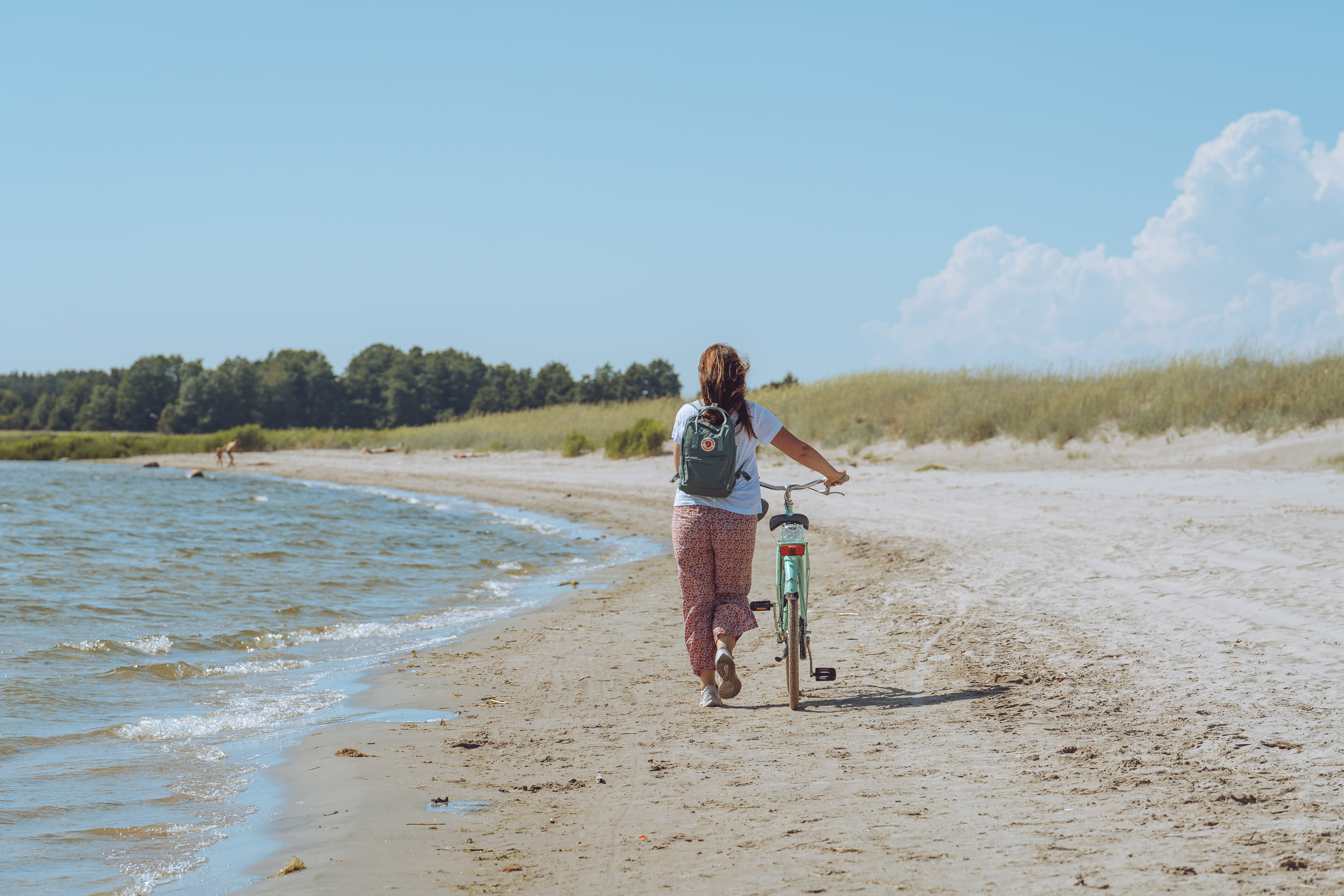 Woman walks bike on the beach on Prangli Island day trip from Tallinn