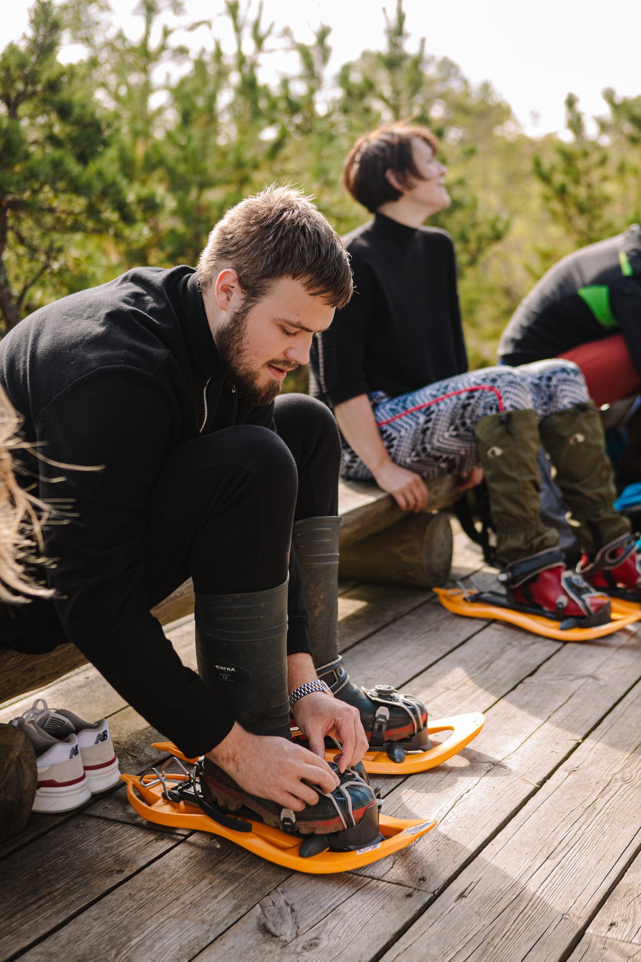 Man putting on bogshoes for a hike in Estonia