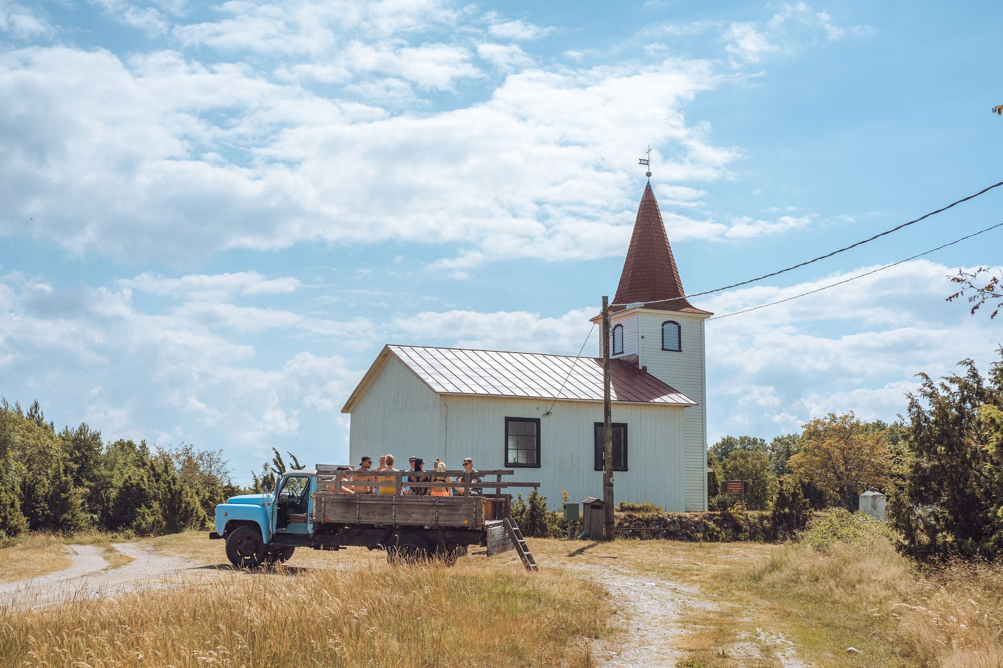 Besucher der Insel Prangli auf der Ladefläche eines alten LKW vor einer Kirche