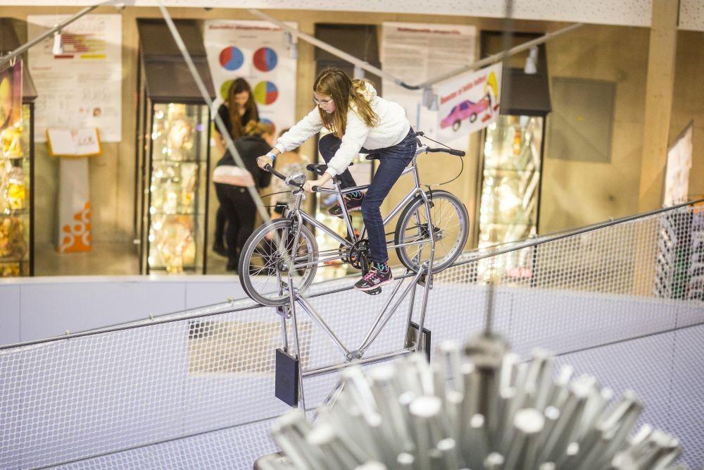 Zinātnes centrs AHHAA drošajiem piedāvā iespēju ar velosipēdu braukt pa griestos esošo trosi