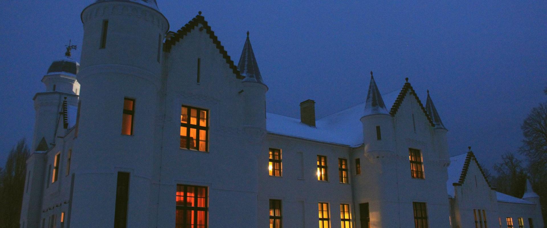 Das Schloss Alatskivi nachts, während aus den Fenstern Licht dringt.
