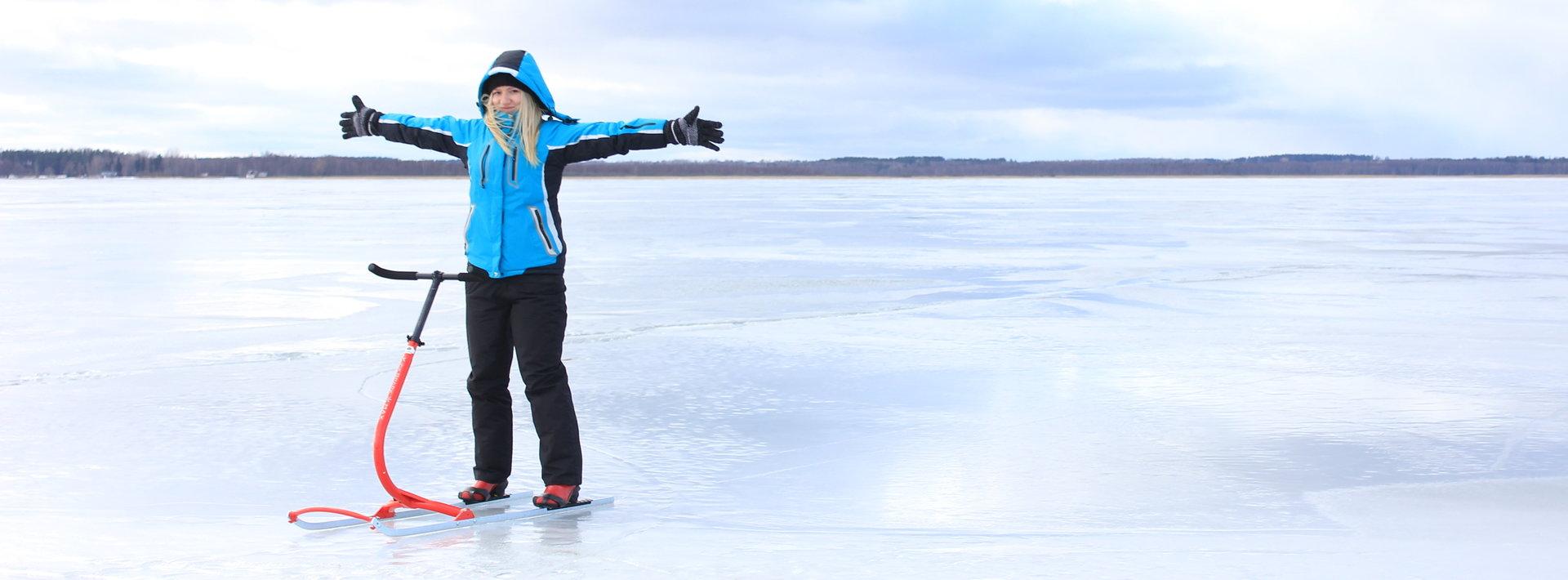 A girl with a blue jacket on a kicksled on the frozen Lake Võrtsjärv