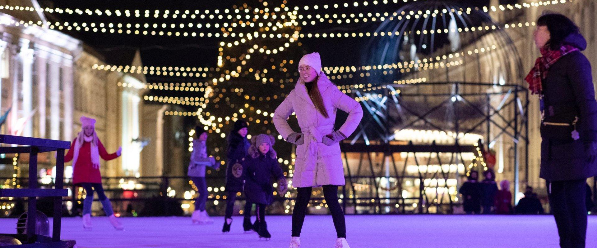 Schlittschuhbahn im Stadtzentrum von Tartu und fröhliche Schlittschuhläufer auf dem Eis