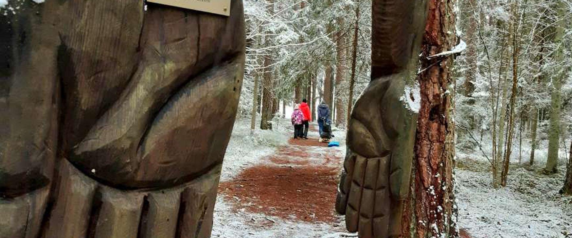 Auf dem Kleinen Kraftweg ist die Skulptur „Hände der Kraft“, in der Ferne Wanderer