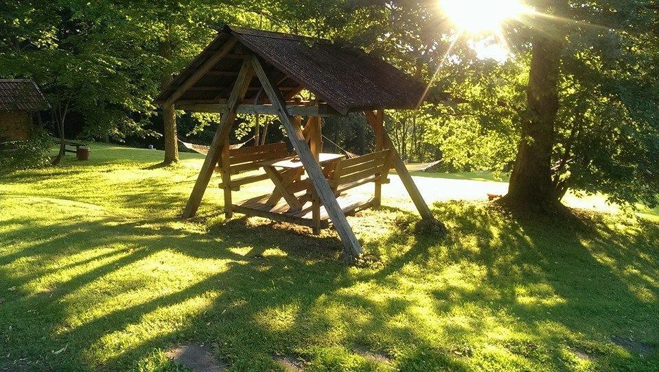 Puidust kiik ja istumisnurk Lasita Puhkemaja rohelises aias Tartumaal, õhtupäikeses