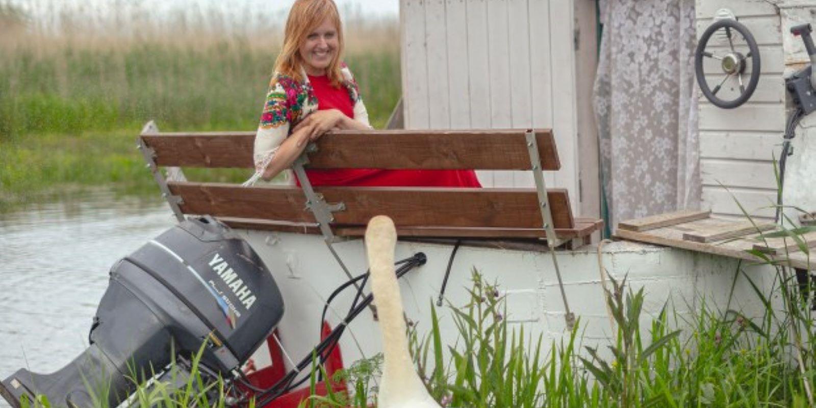 The hostess of Mesi tare guesthouse sitting in a boat house and talking to a swan