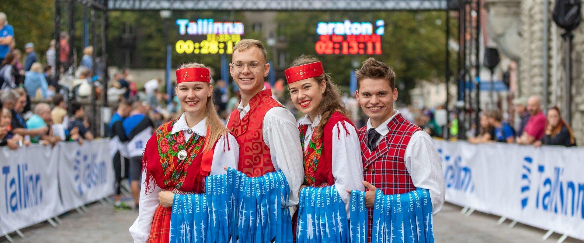 Estonian folkdancers holding the medals of Tallinn Marathon
