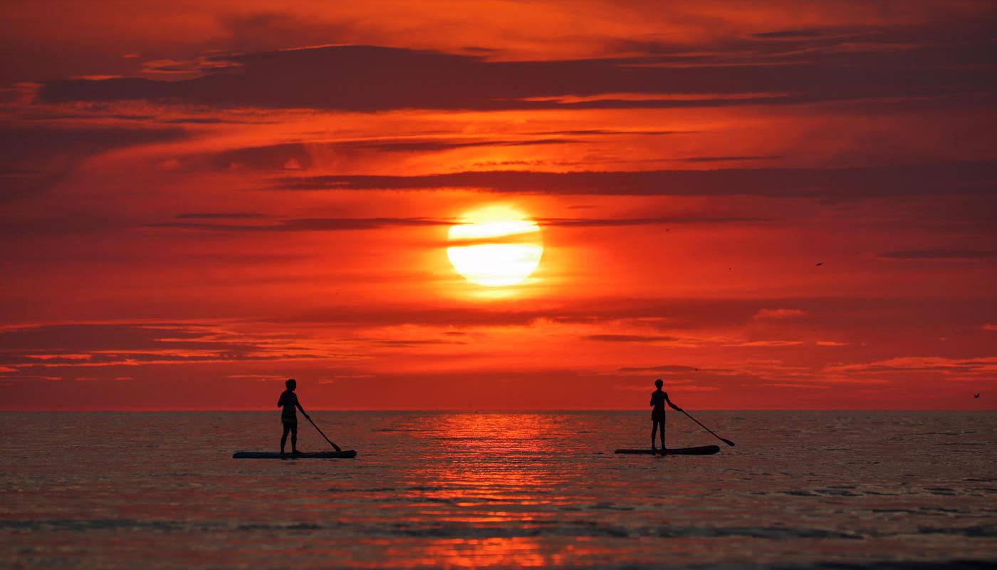 Kaks aerusurfajat päikeseloojangu ajal surfamas