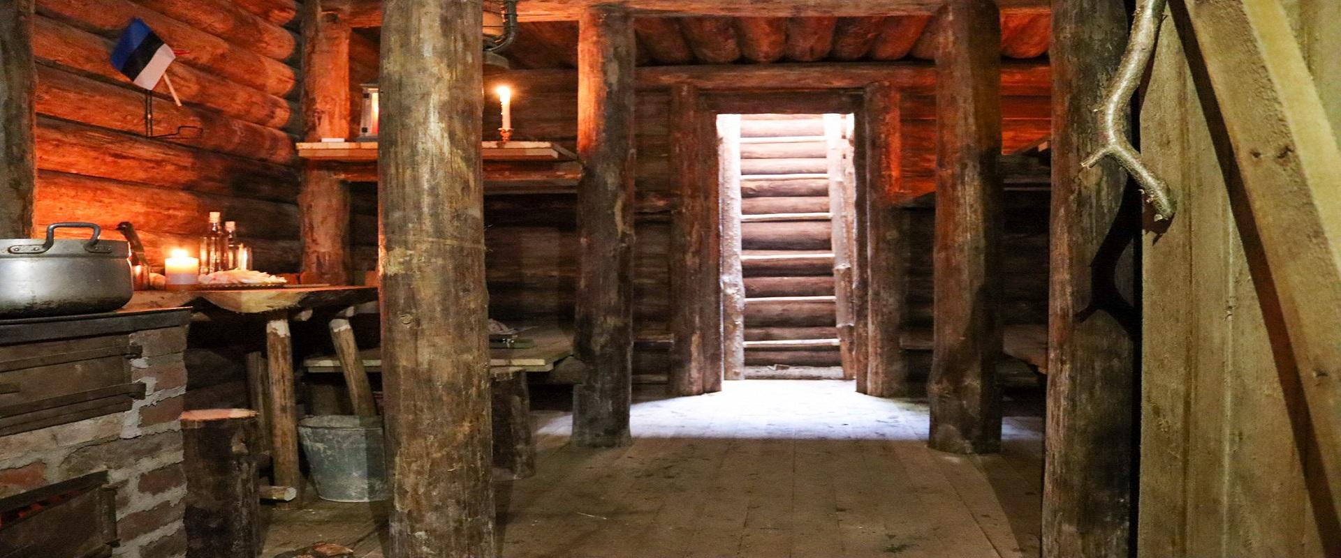 Main room of the bunker, which has six bunk beds, a stove, an exit, and an entrance to the tunnel