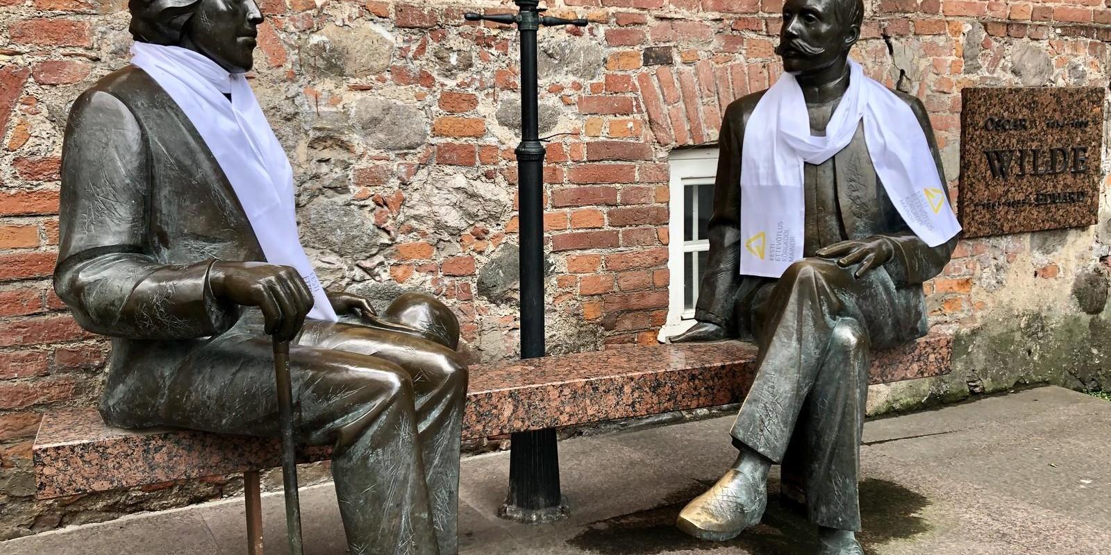 Two men, Eduard Vilde and Oscar Wilde, talking on a stone bench