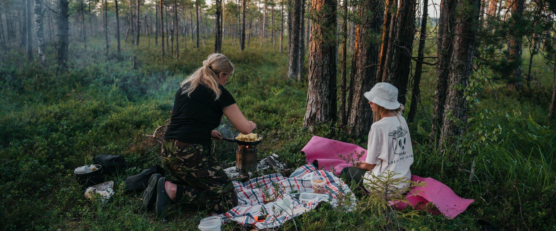 Pildil rabas toitu valmistavad ja pikniku pidavad inimesed