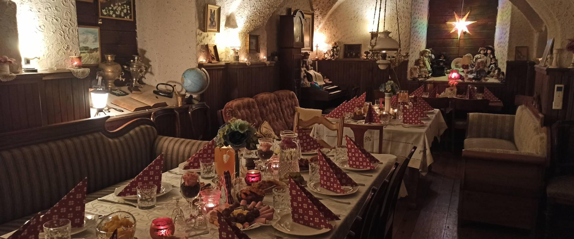 Kuvassa Mäe-Kodan juhlapöytä. Pöydällä punaisia valkotäpläisiä lautasliinoja, jotka on taitettu kolmion muotoon. Lämpimiä sävyjä ja viihtyisää tunnelmaa. Katettu pöytä herkkuineen