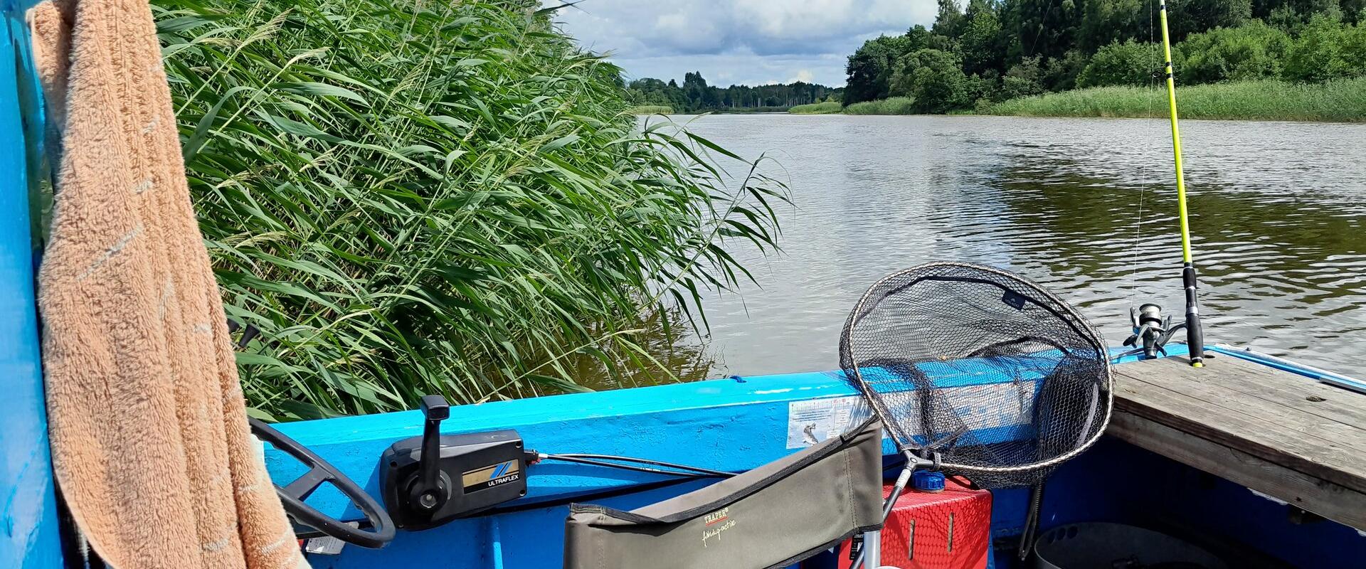 Kalastusvarustus Humala Kalabaasi paadis Emajõel, taustal rahulik loodus ja roostik.