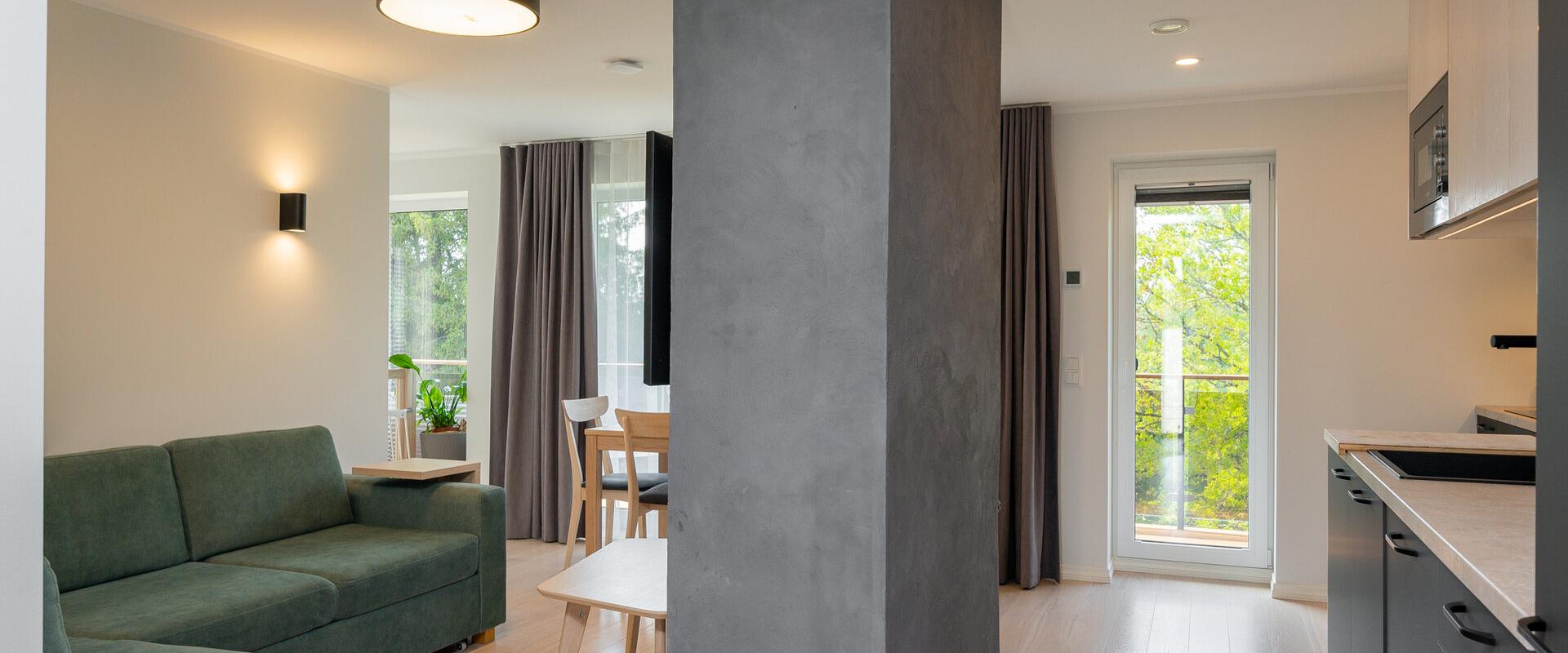 Kalda Villa valgusküllane elutuba rohelise diivani ja köögiga