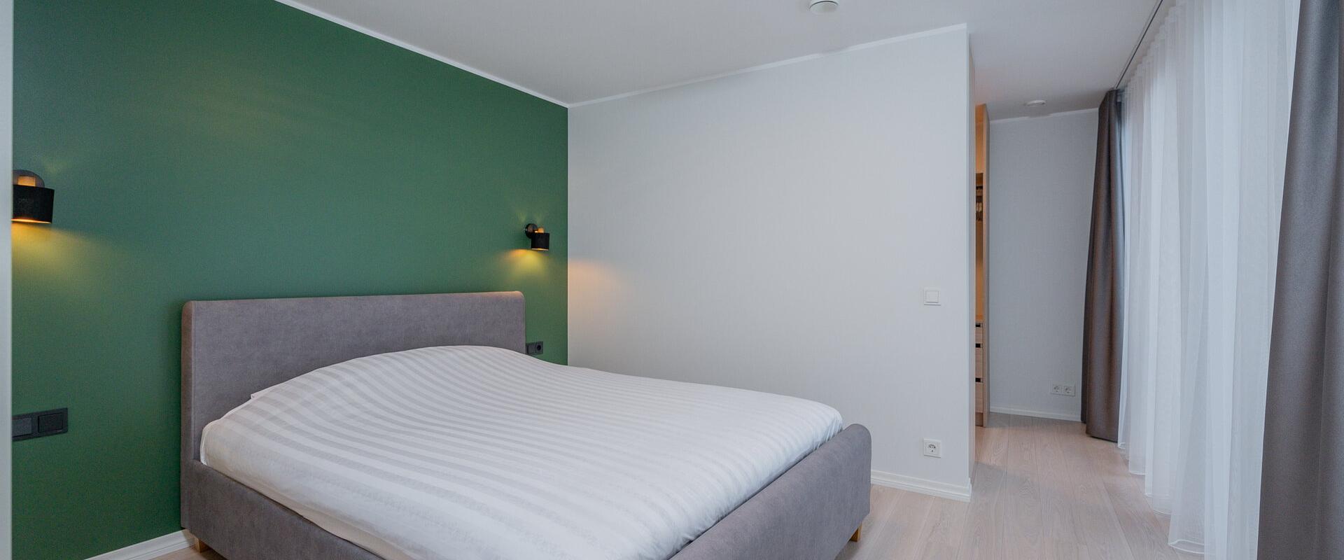 Kalda Villa magamistuba rohelise seina ja mugava voodiga