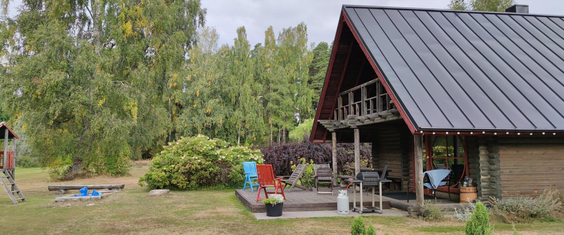 Markna Tourist Farm Sauna House - sunny terrace with barbecue. There is a playhouse and sandbox for children in front of the terrace.