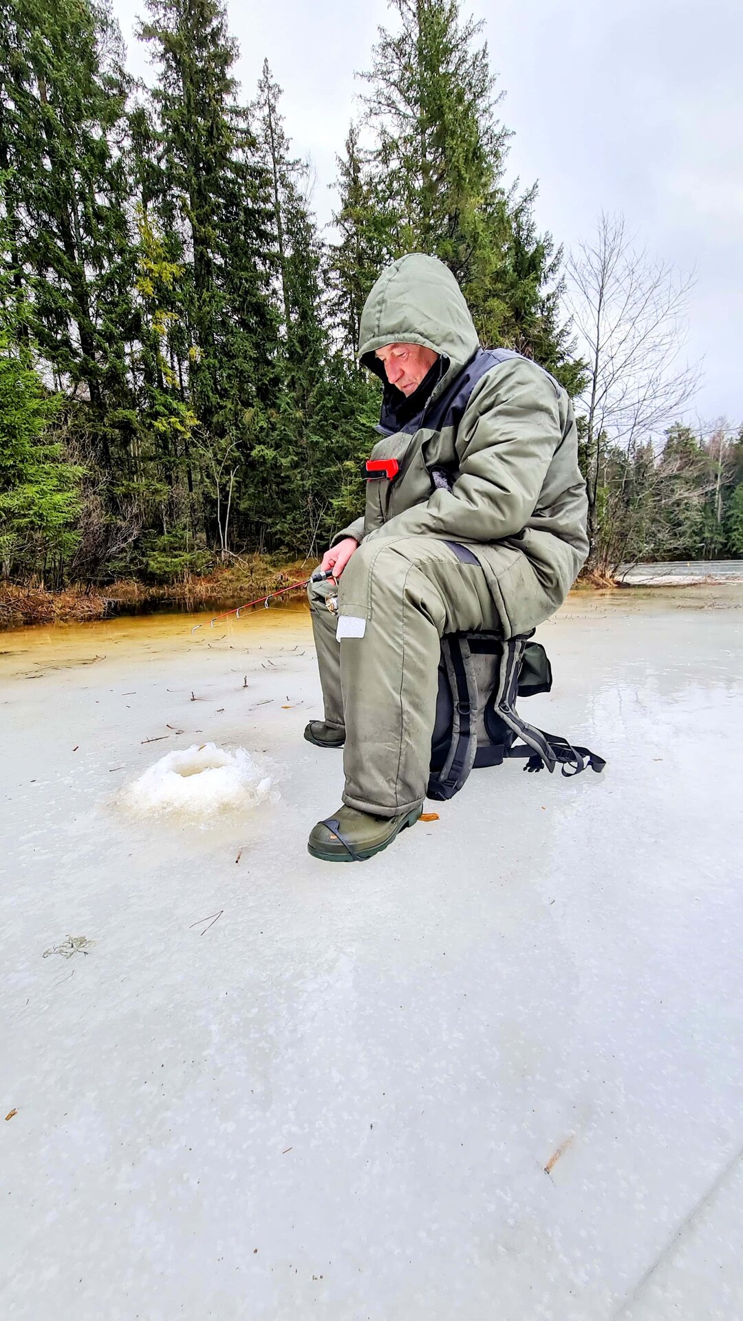 Mees järvel istudes jääaugust kala püüdmas