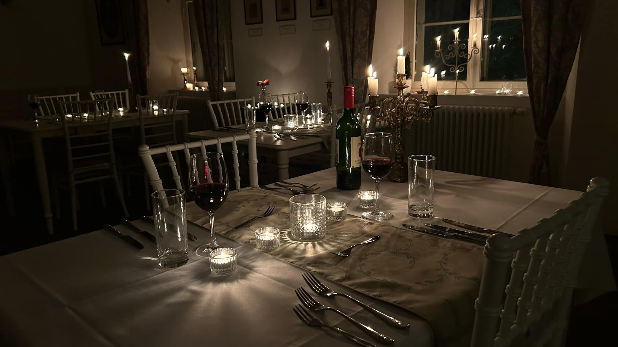 Romantiliselt kaetud laud Luke mõisas, kus küünlavalgel säravad veinipokaalid ja hubane atmosfäär