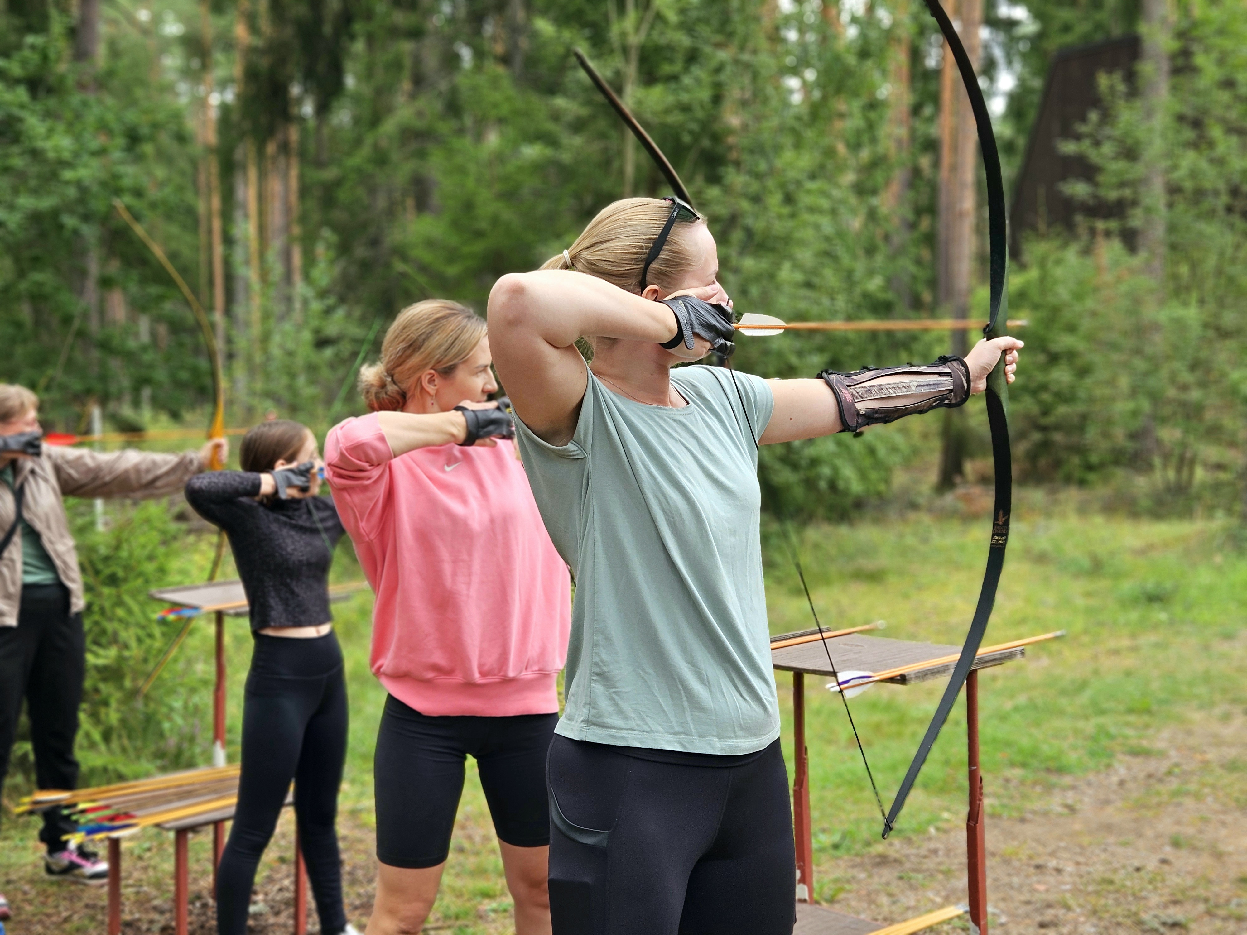 Group aiming with bows outdoors.