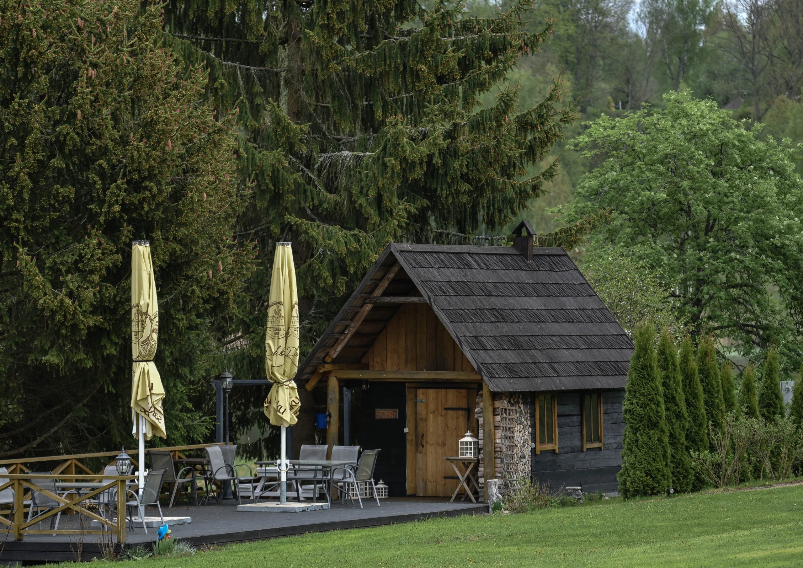 Traditsiooniline suitsusaun Ööbikuoru villas, sauna eest on terrass ja istumisala, sauna ümber mets.