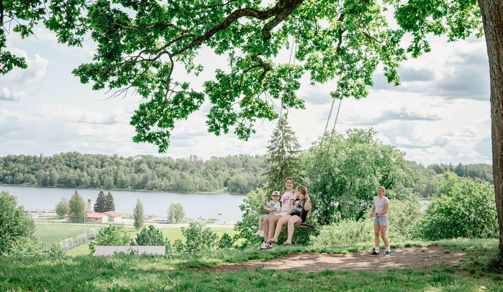 Lapsed tamme all kiikumas, suvine Viljandi taustal