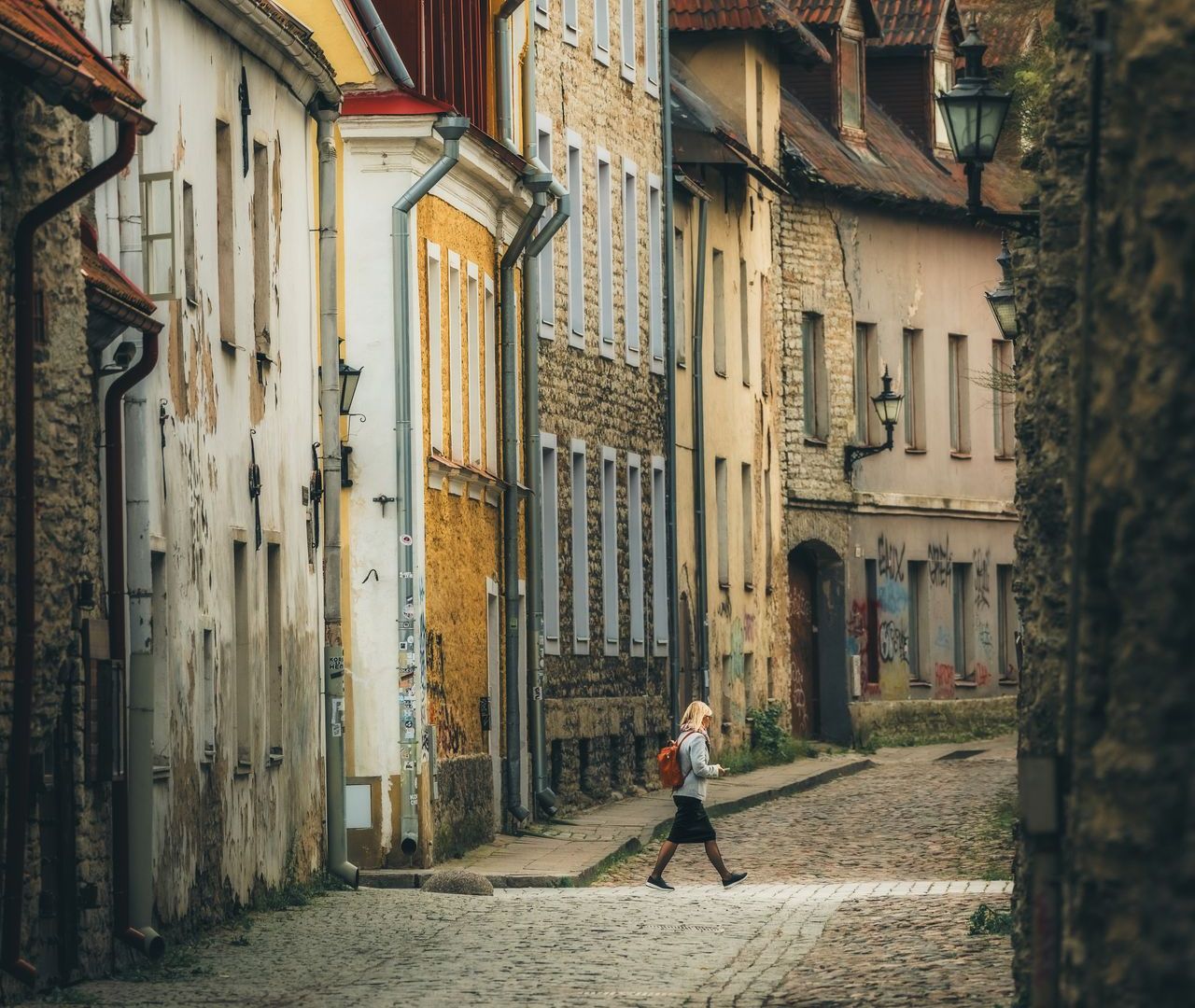 Tüdruk jalutamas sügisesel päeval mööda Tallinna vanalinna munakivitänavat.